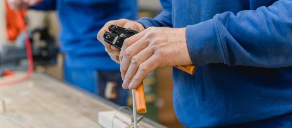 Ein Mann in einem blauen Hemd hält einen Schraubenzieher in der Hand.