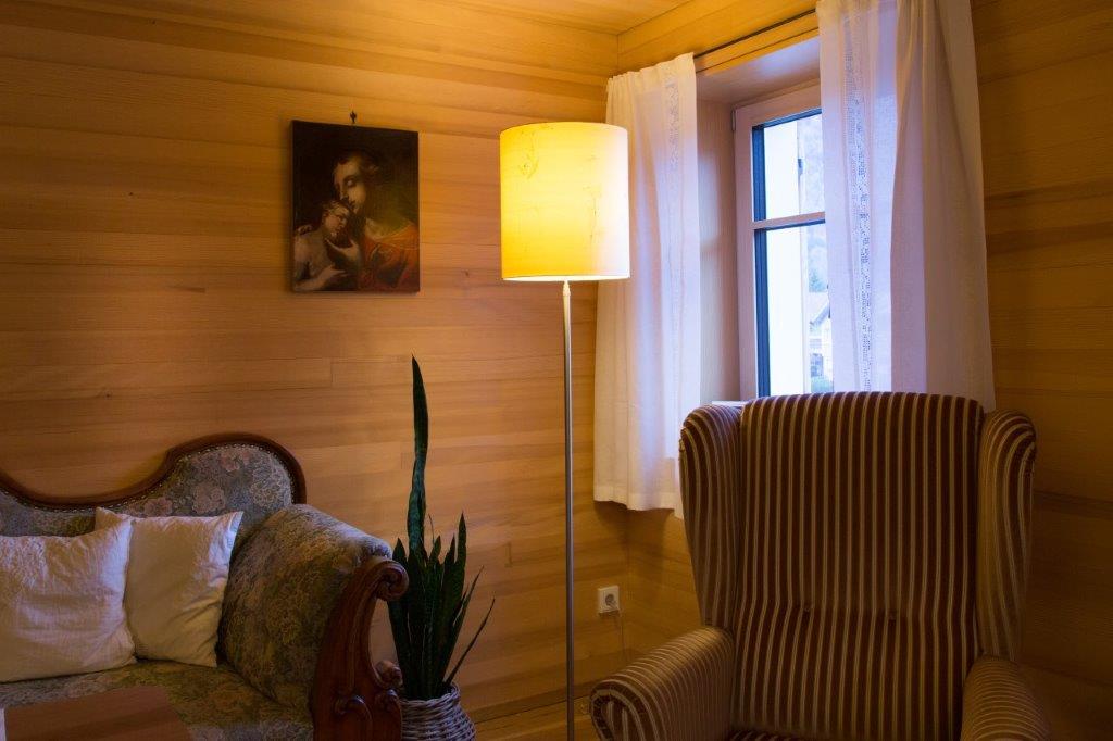 Ein Wohnzimmer mit Sofa, Sessel, Lampe und Gemälde an der Wand.