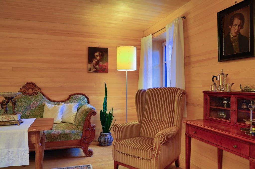Ein Wohnzimmer mit Couch, Sessel, Tisch und Lampe.