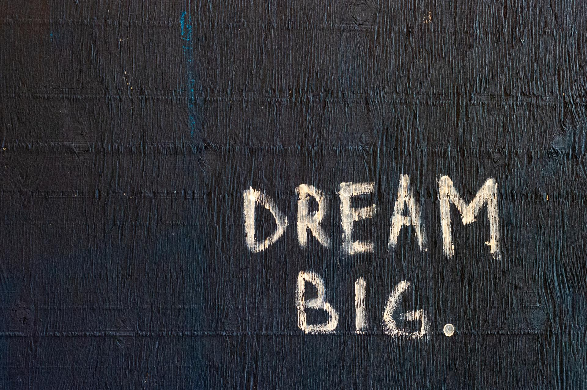 Black background with handwritten words that say Dream Big with a caption that says 