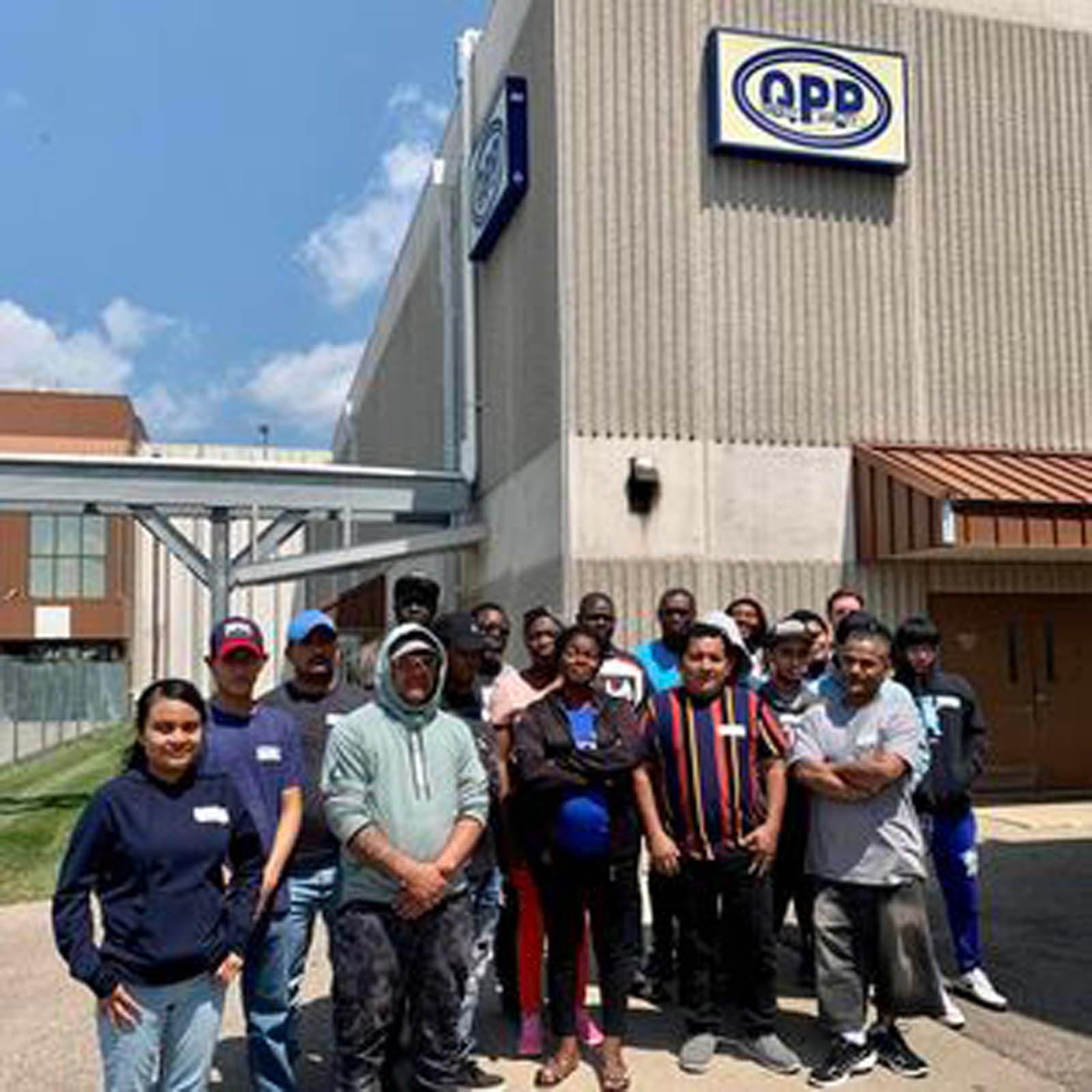A group of people standing together outside a building with an OPP sign on the exterior wall.