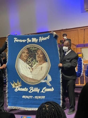 Blue memorial banner with oval portrait, gold text, and two men standing beside it in a church interior