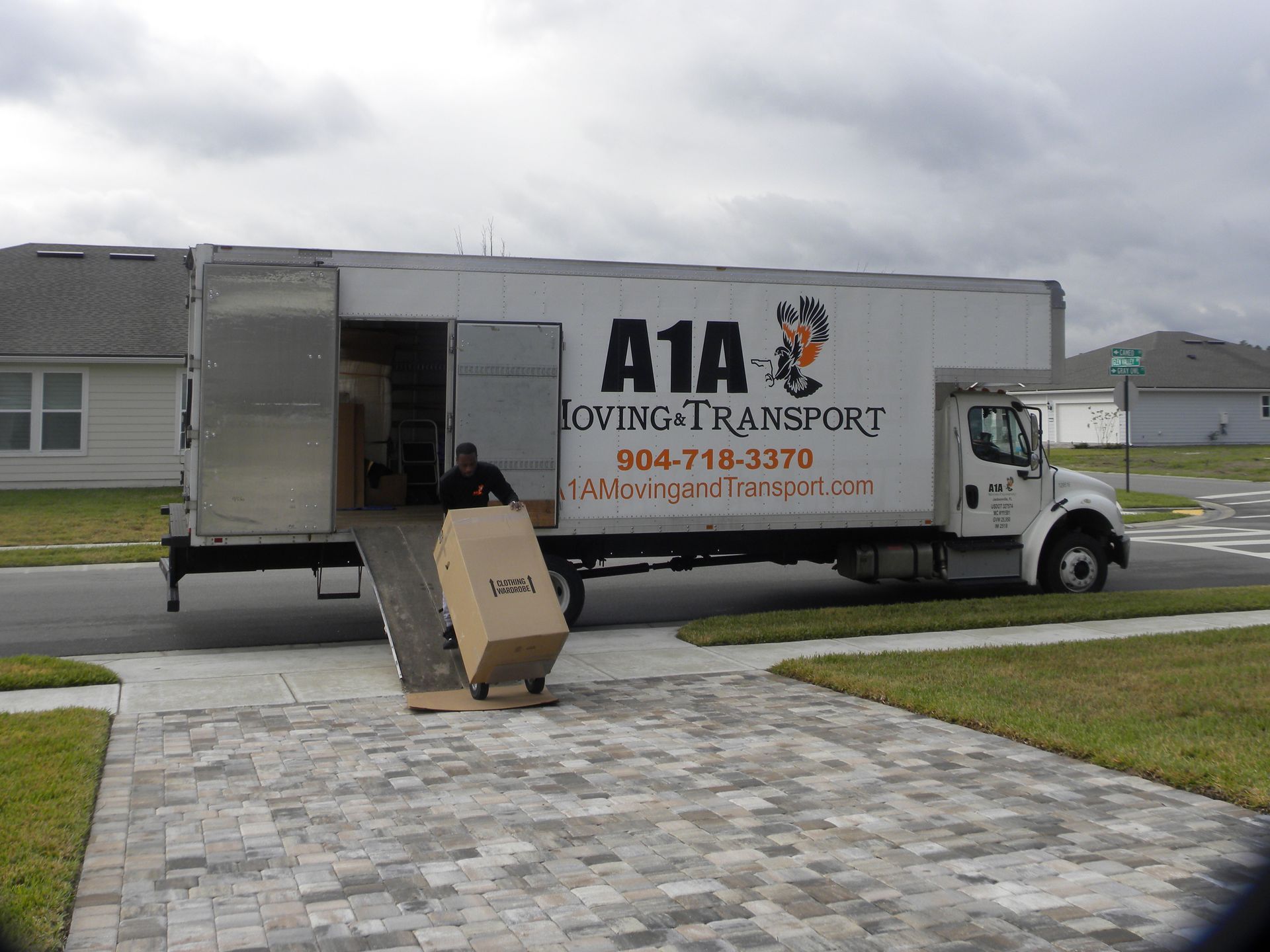 Sandblasting and Rust Removal in Harford County, MD Moving truck parked on a driveway, with a person loading a large box. Cloudy sky.