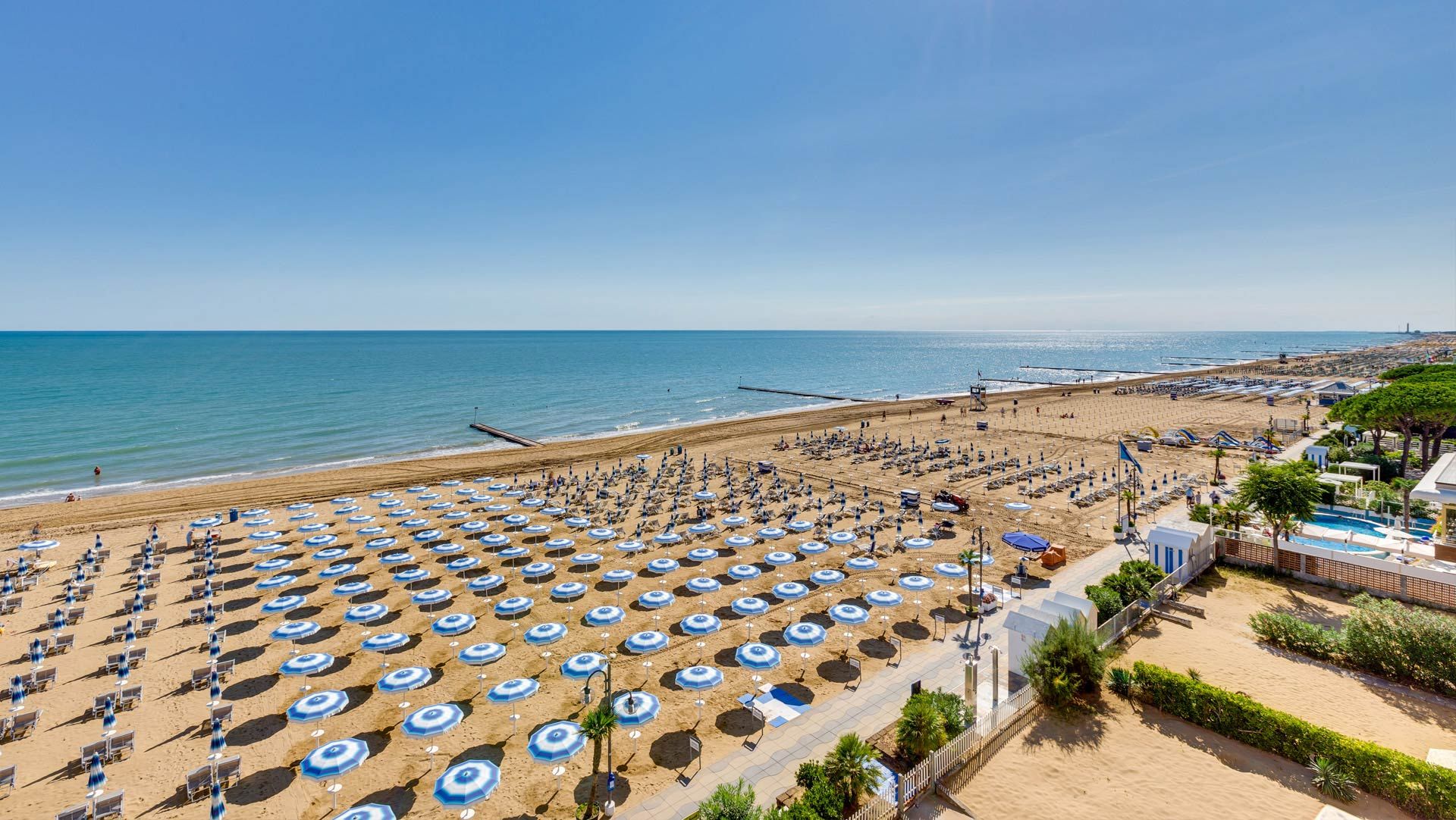 An aerial view of a beach filled with lots of blue umbrellas.