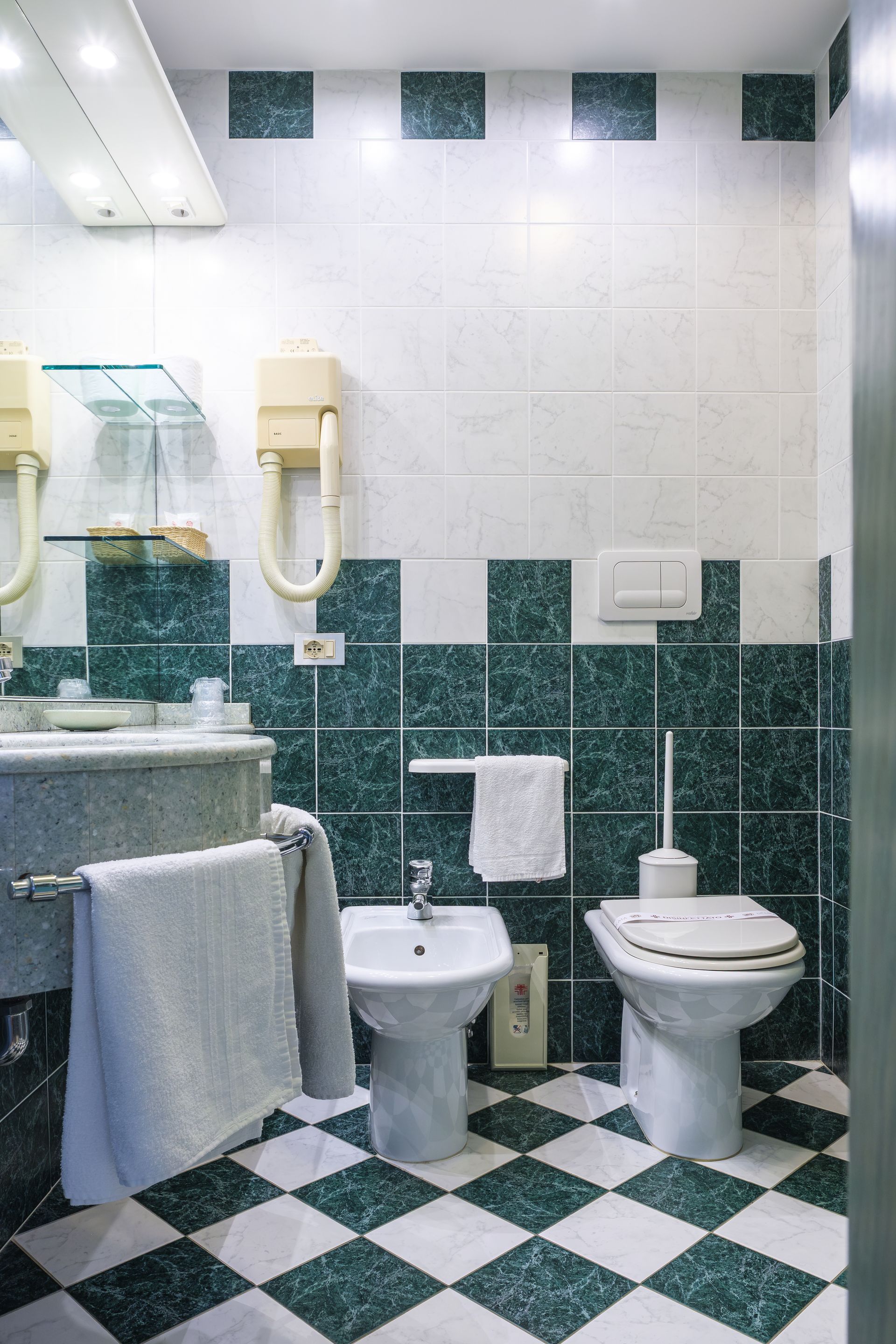 Un bagno con piastrelle verdi e bianche e pavimento a scacchi.