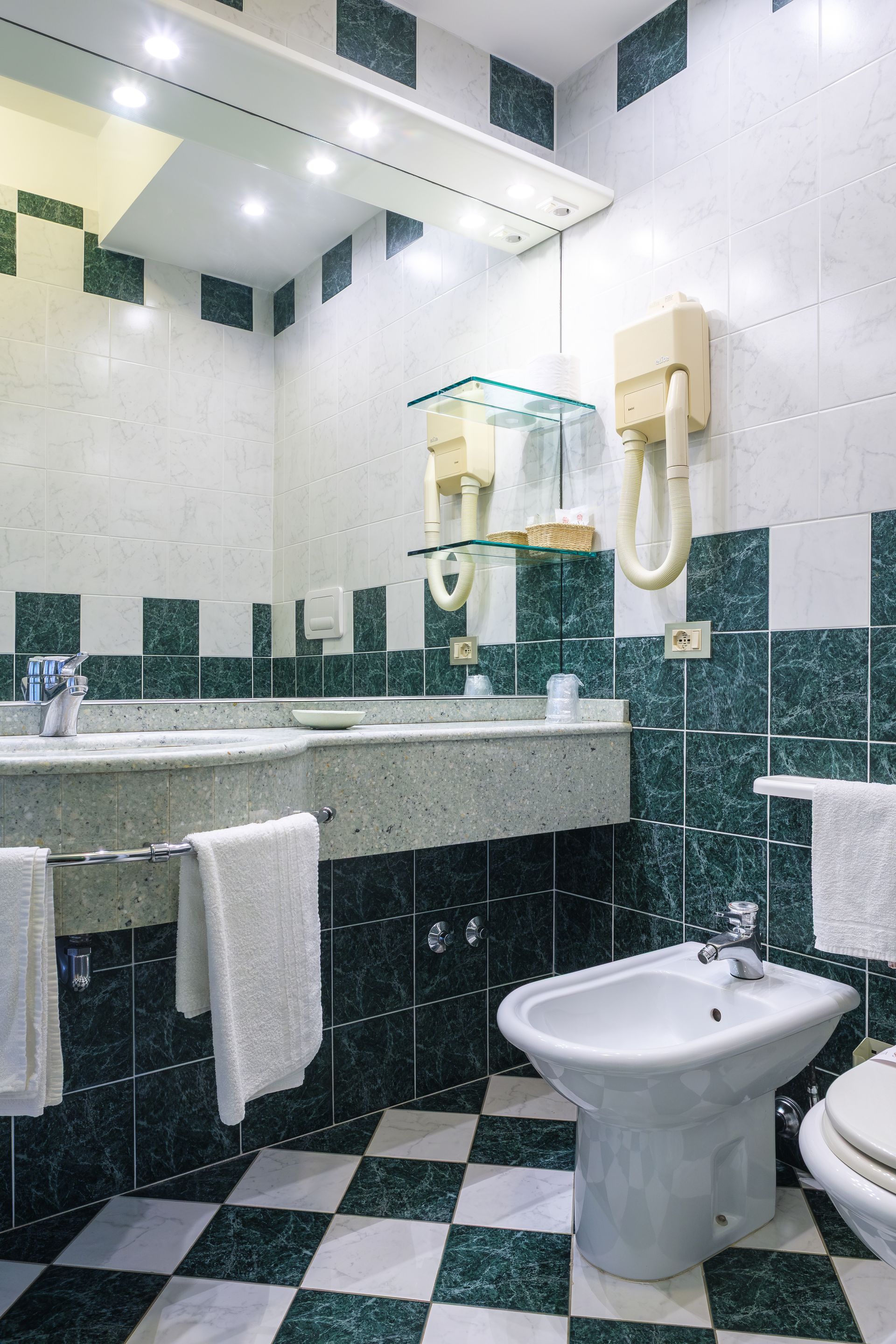 Un bagno con piastrelle verdi e bianche e un bidet.