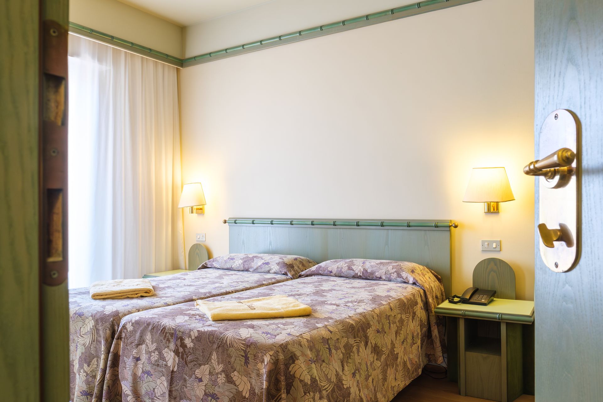 Una camera d'albergo con due letti e un comodino.