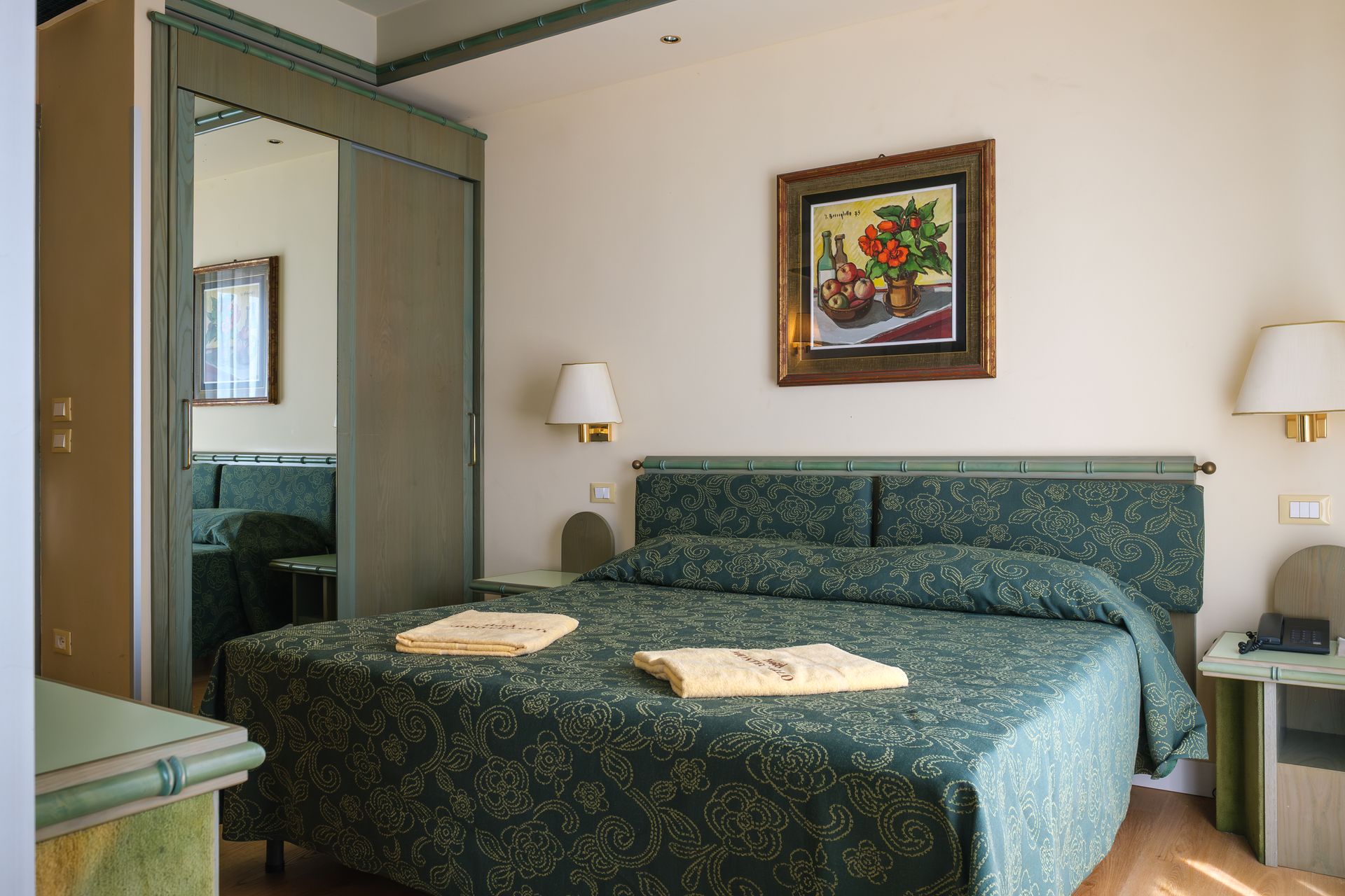 Una camera d'albergo con un letto grande e un dipinto sul muro.