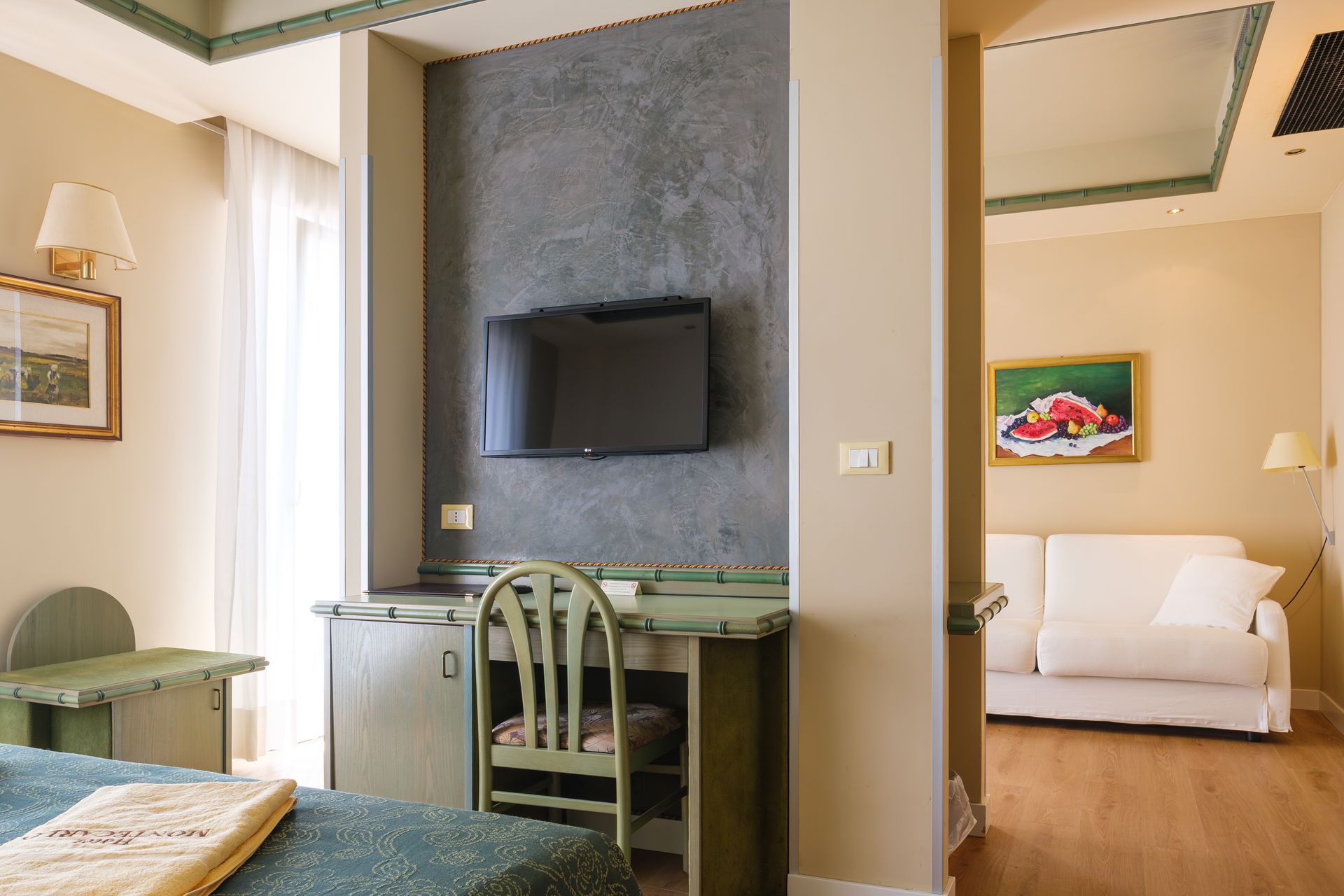 Una camera d'albergo con un letto, una scrivania, una sedia e una televisione.