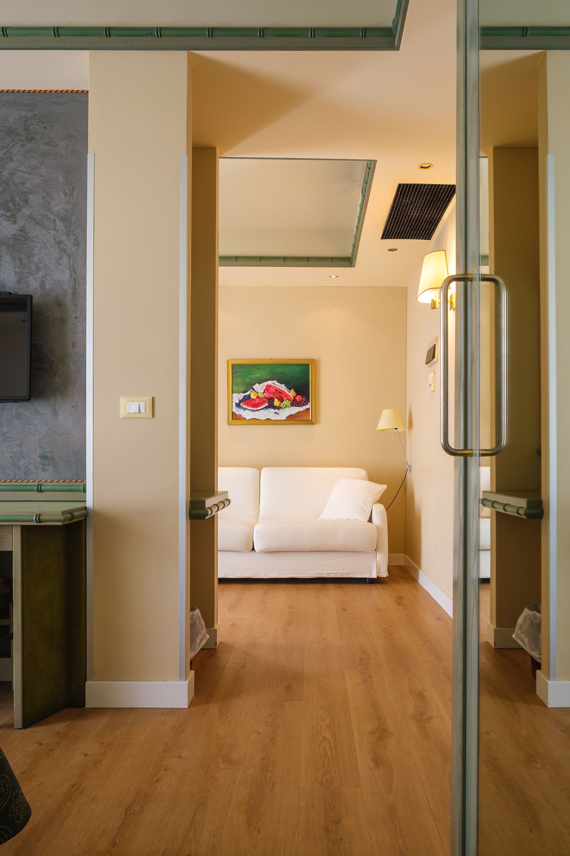 Una camera d'albergo con un divano e una TV a parete.