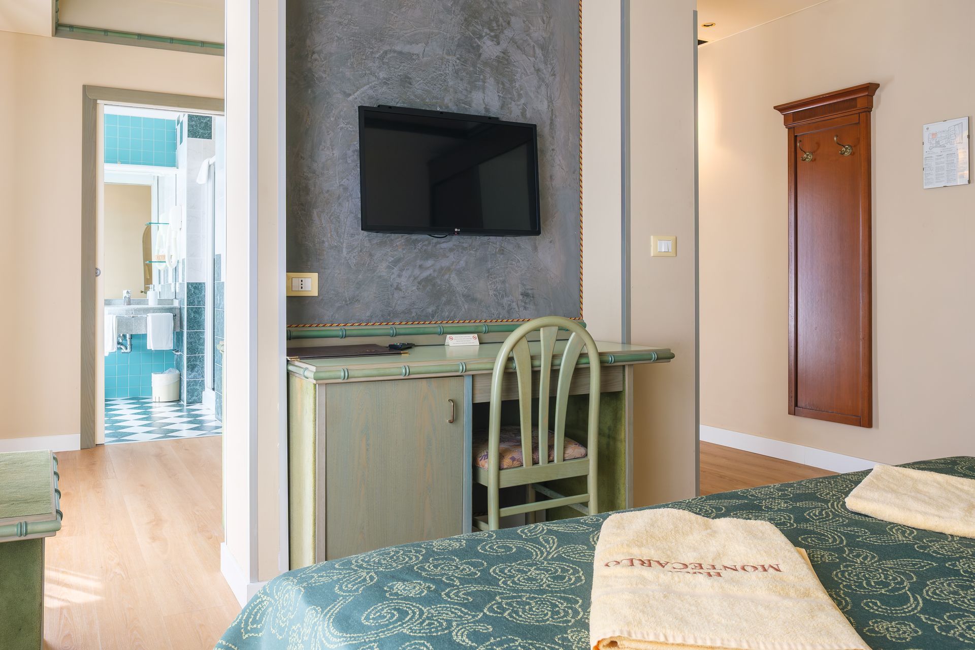 Una camera d'albergo con un letto, una scrivania, una sedia e una televisione.