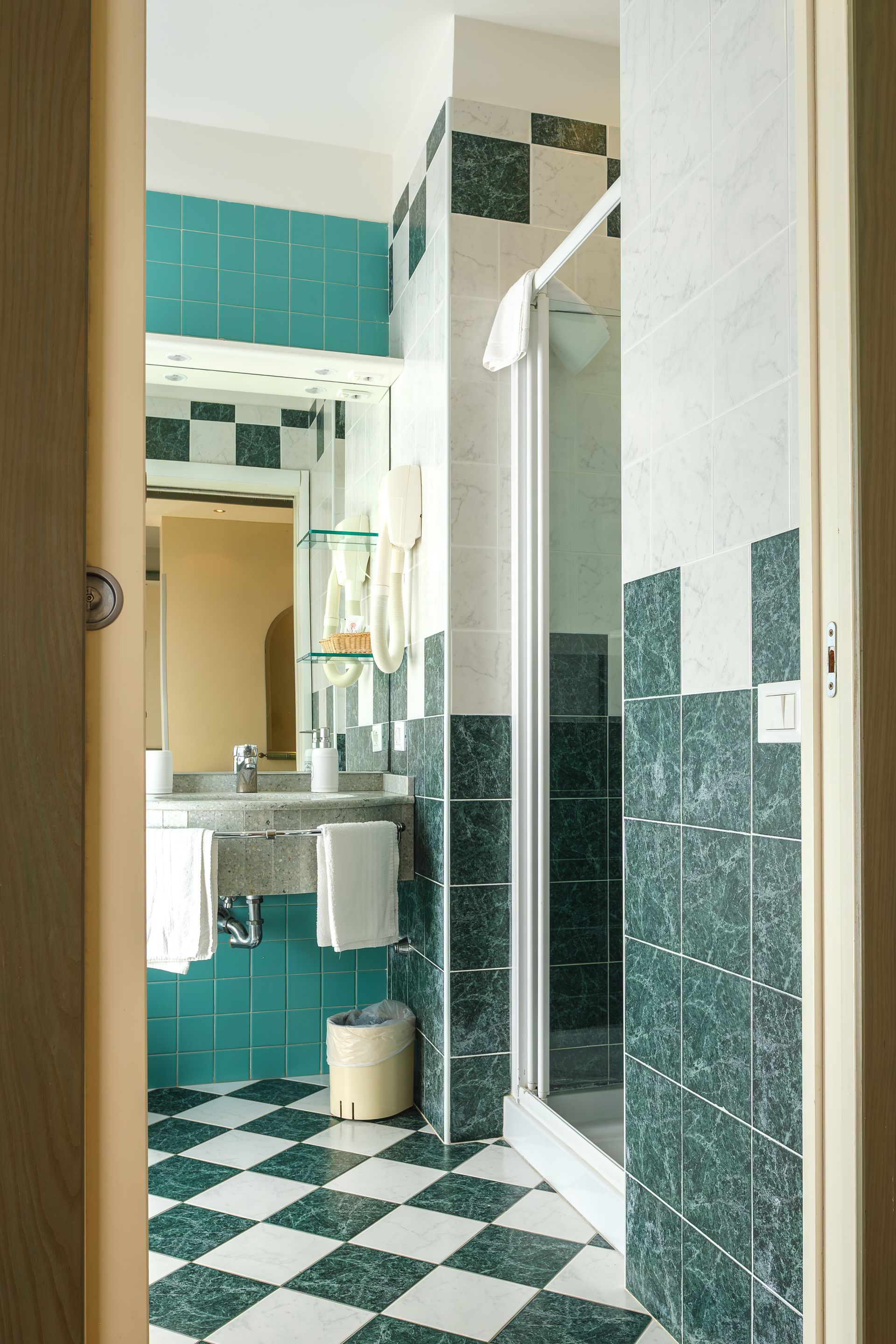 Un bagno con piastrelle verdi e pavimento a scacchi.