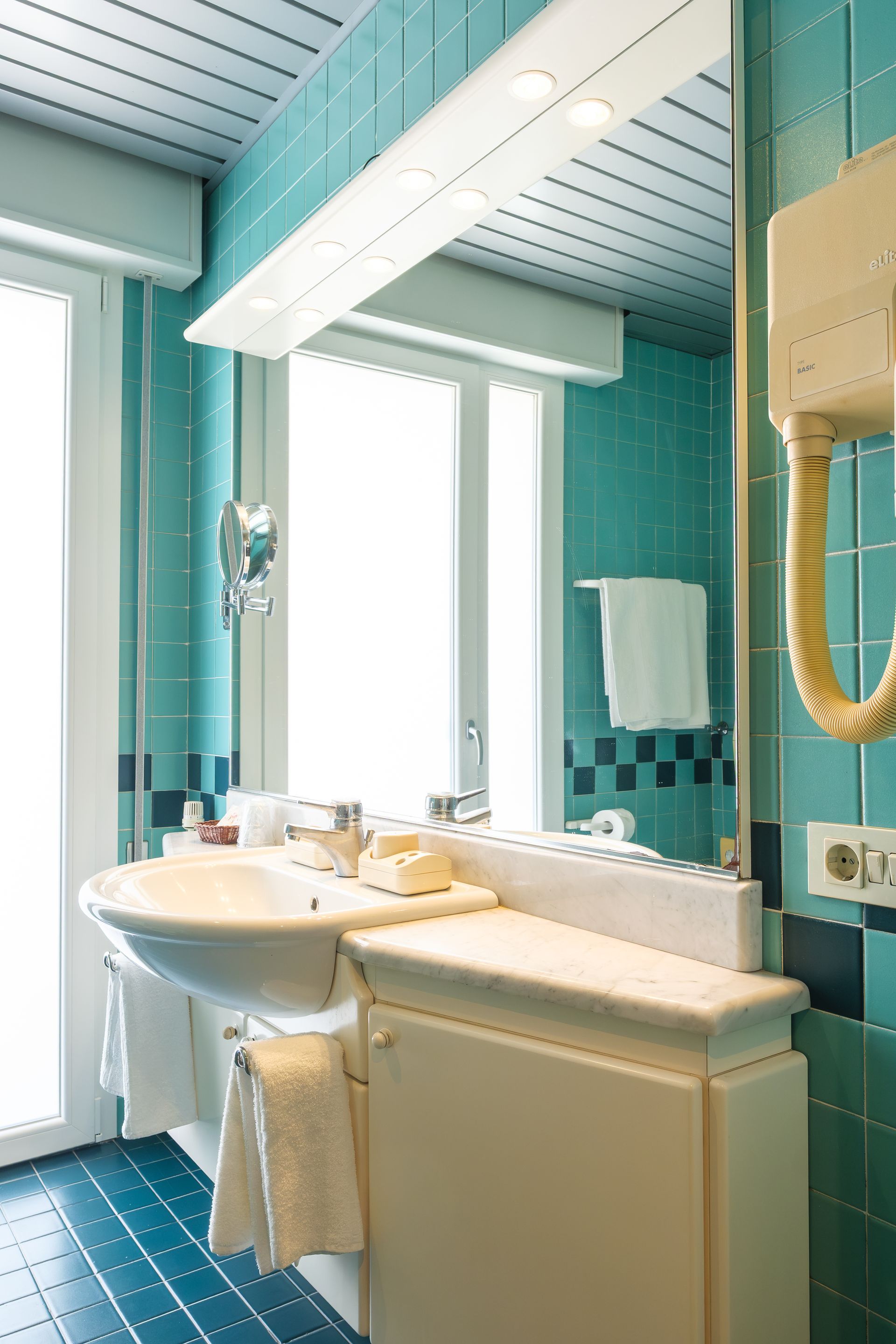 Un bagno con lavandino, specchio e asciugacapelli.