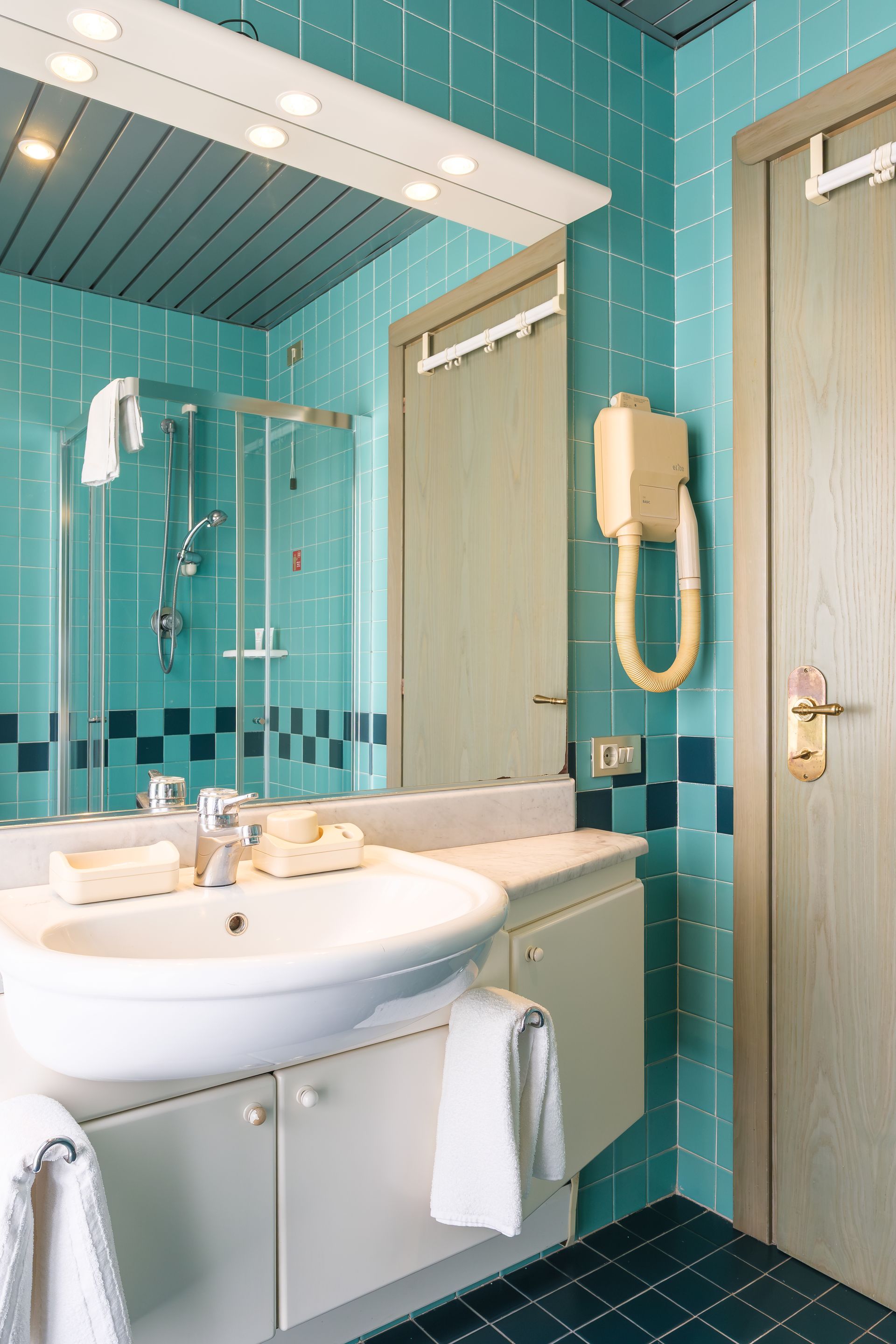 Un bagno con piastrelle blu, lavandino e specchio.