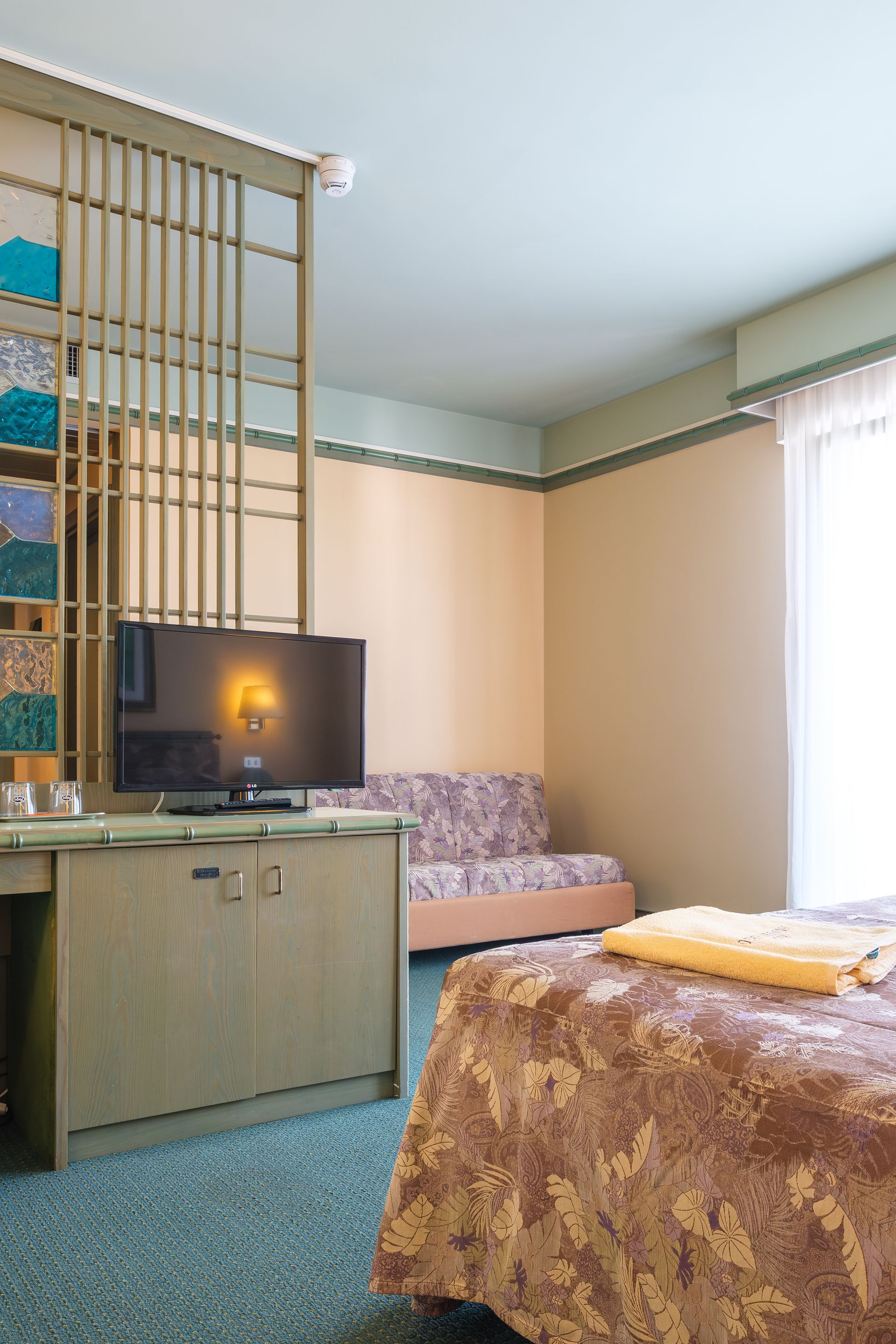 Una camera d'albergo con un letto, un divano e una televisione.