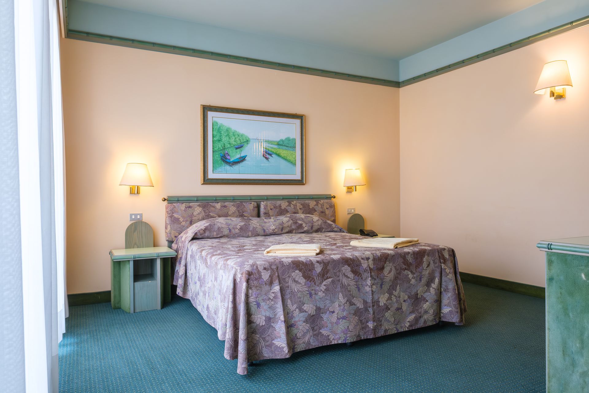 Una camera d'albergo con un letto e un dipinto sul muro.