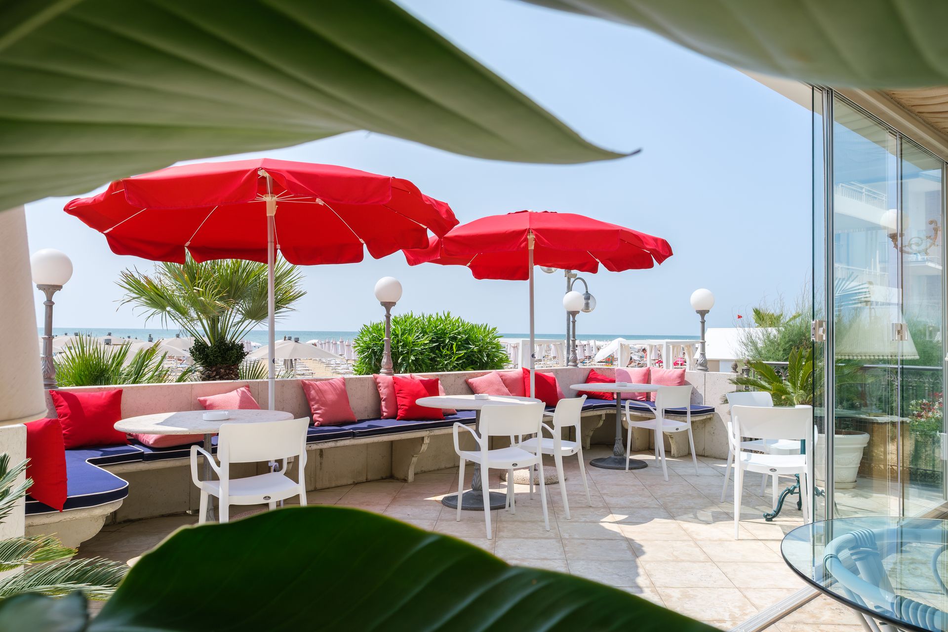 Un patio con ombrelloni rossi e sedie bianche.