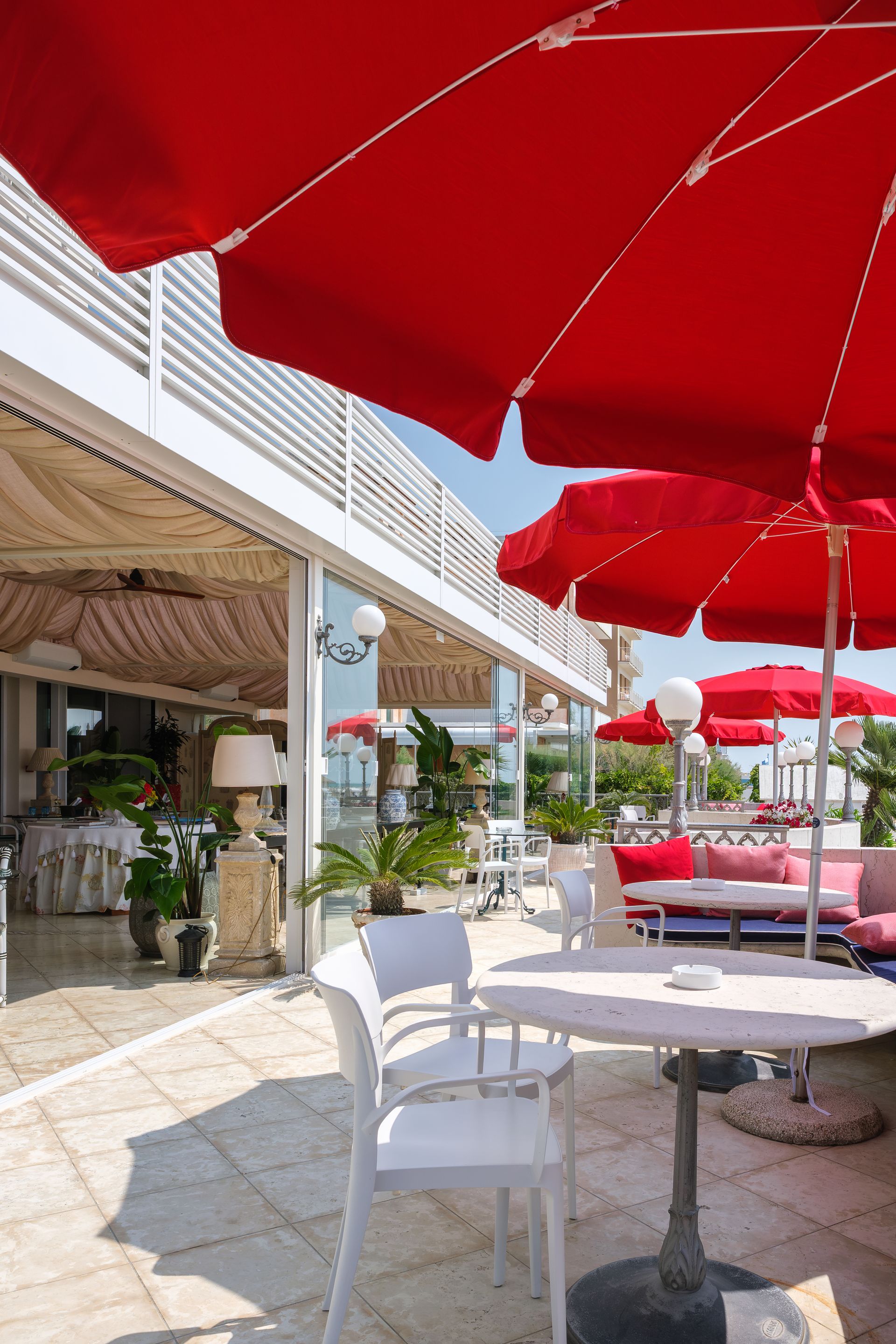 Un ristorante con ombrelloni rossi e sedie bianche.
