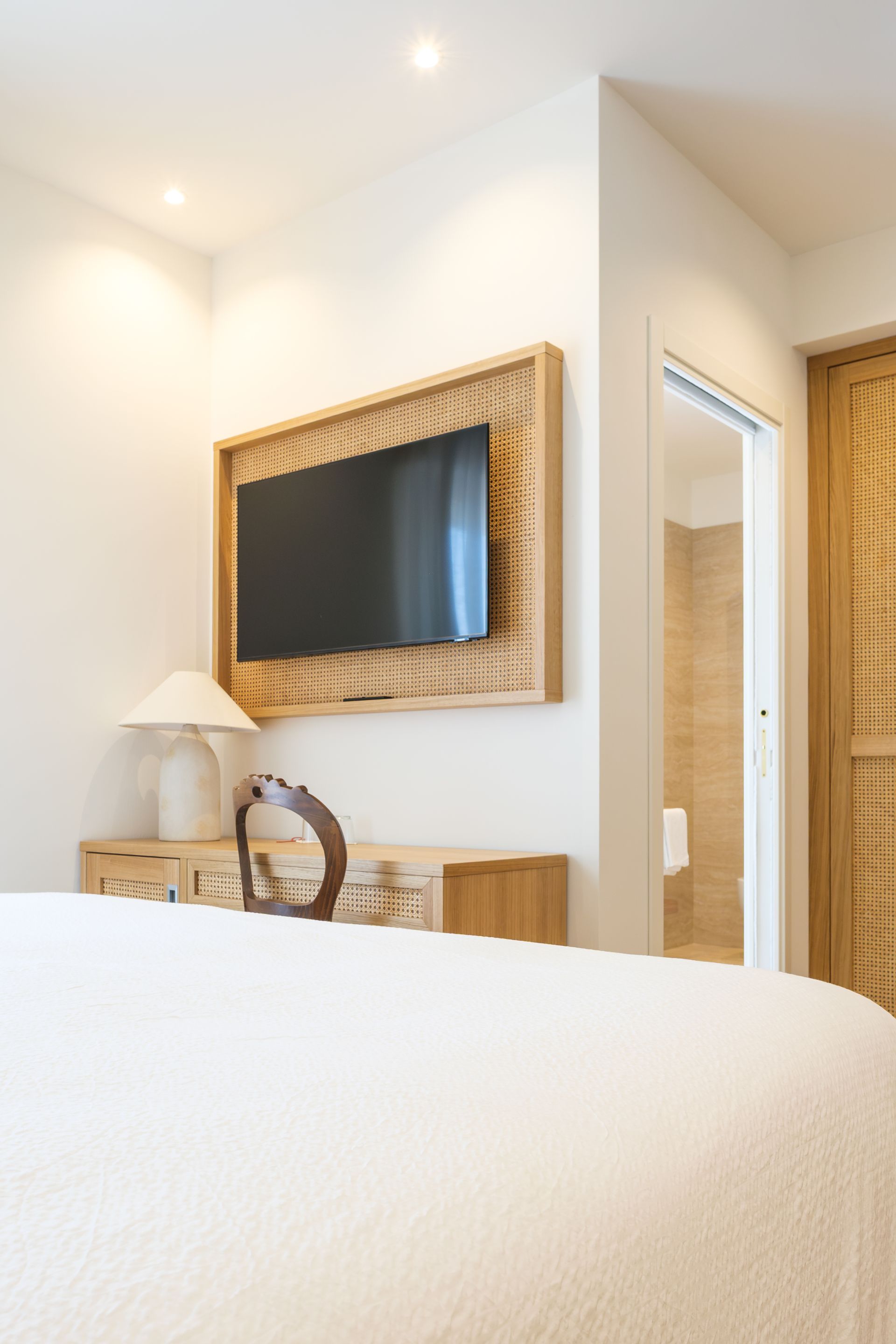 Una stanza d'albergo con un letto, una scrivania e una televisione sul muro.