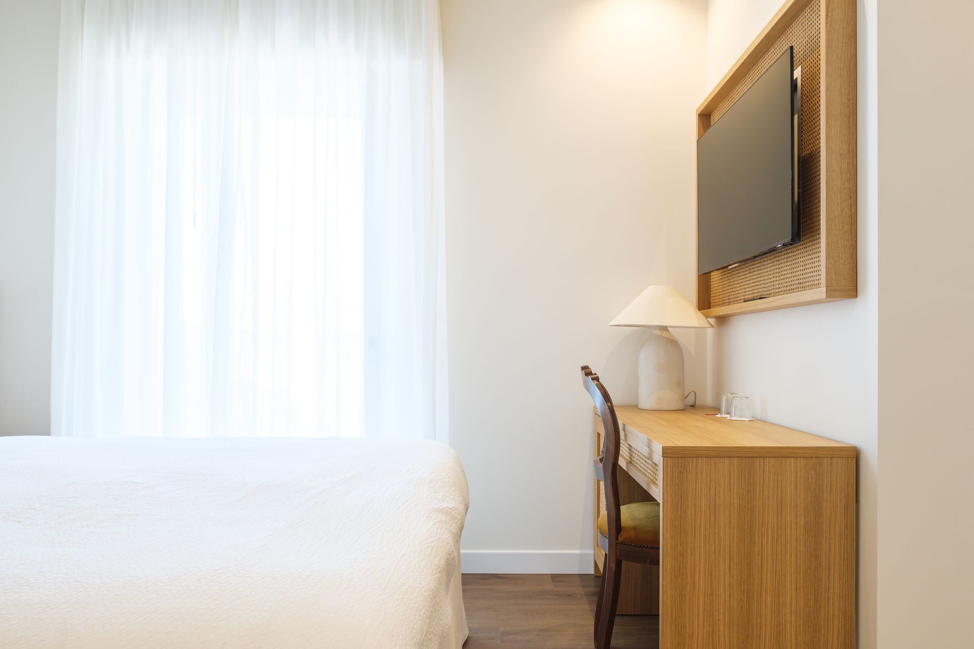 Una camera d'albergo con un letto, una scrivania, una sedia e una televisione.