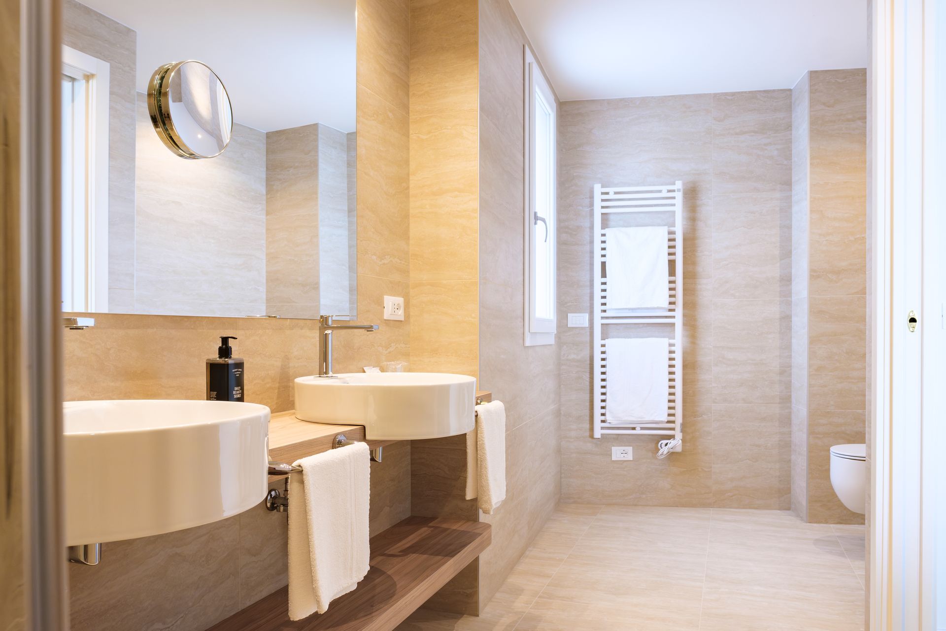 Un bagno con due lavandini, un water e uno specchio.