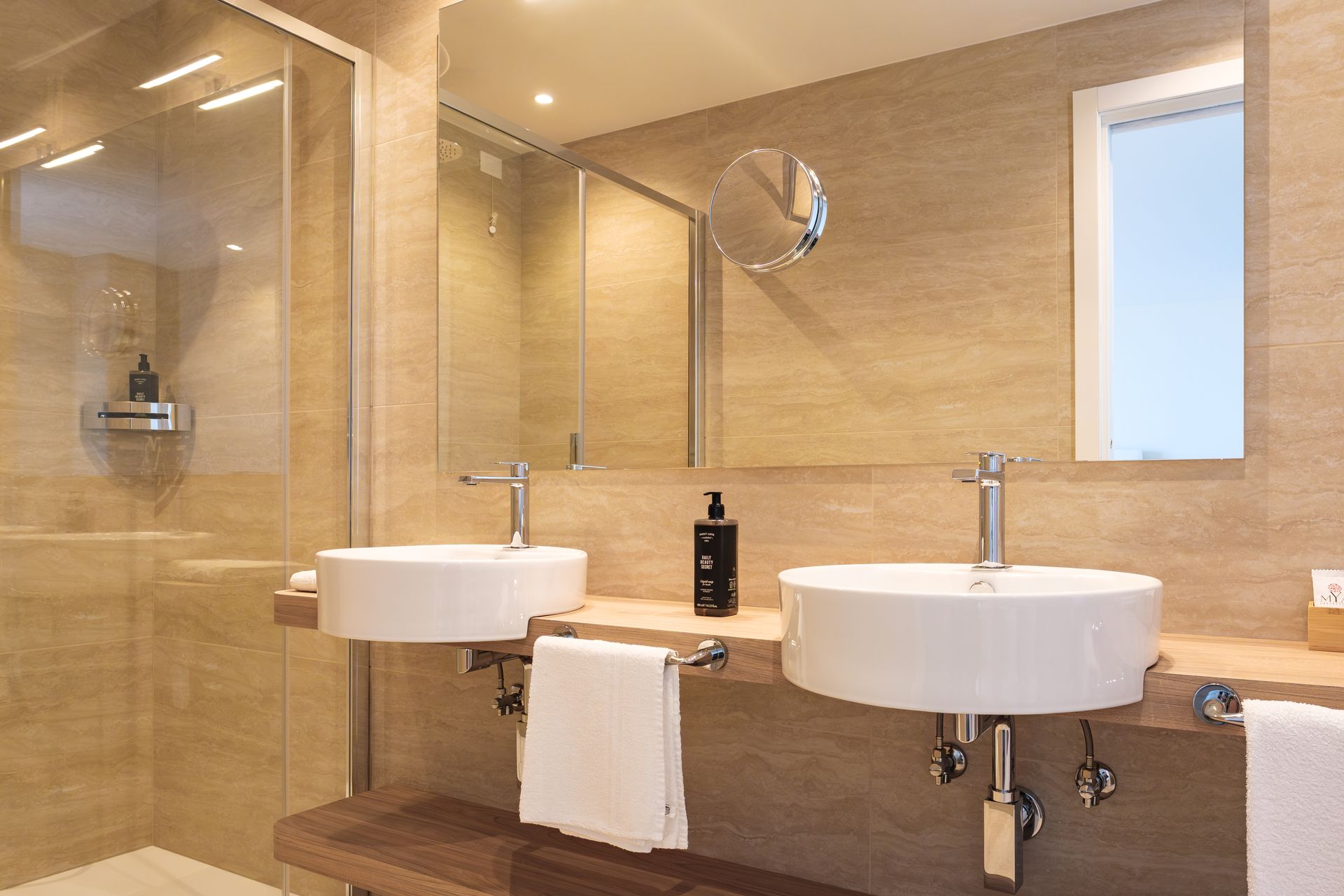 Un bagno con due lavandini, uno specchio e una cabina doccia.