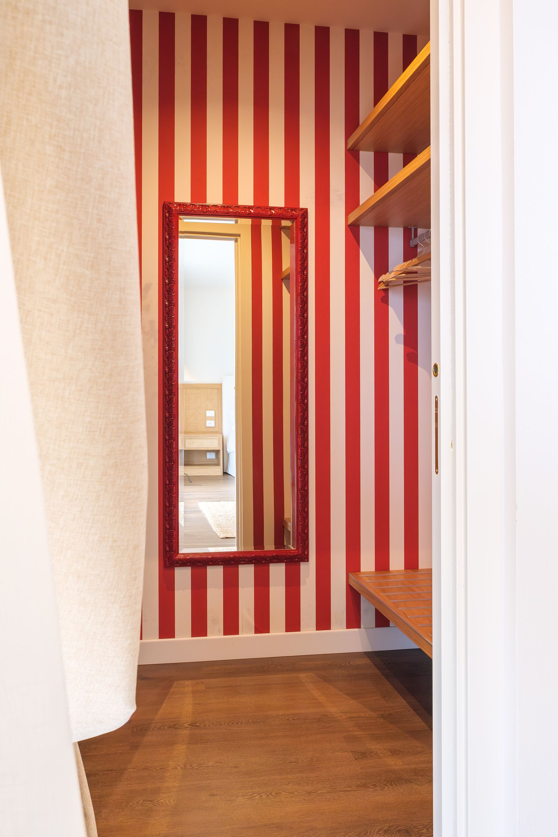 Una stanza con strisce rosse e bianche sul muro e uno specchio.