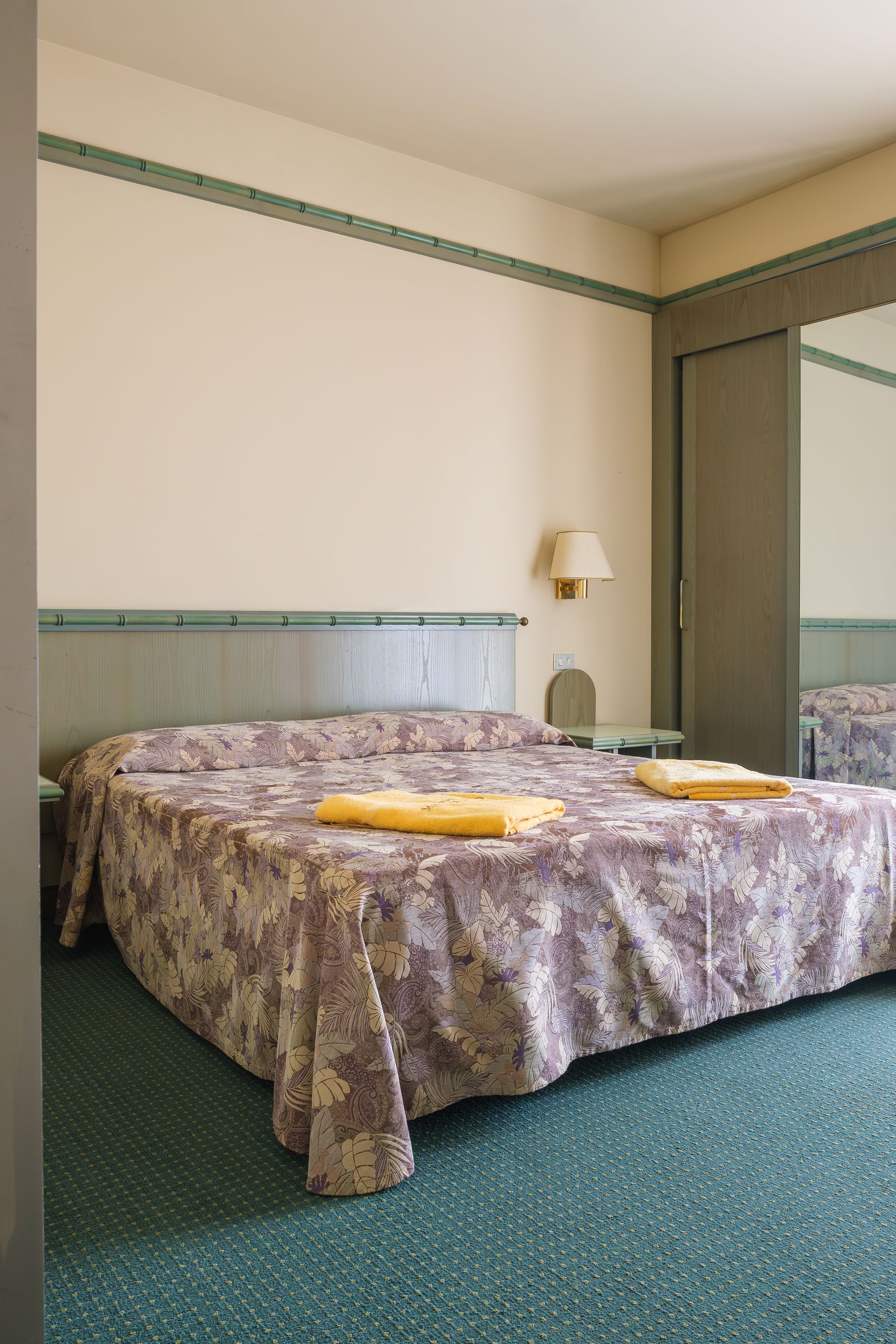 Una stanza d'albergo con un letto e uno specchio.