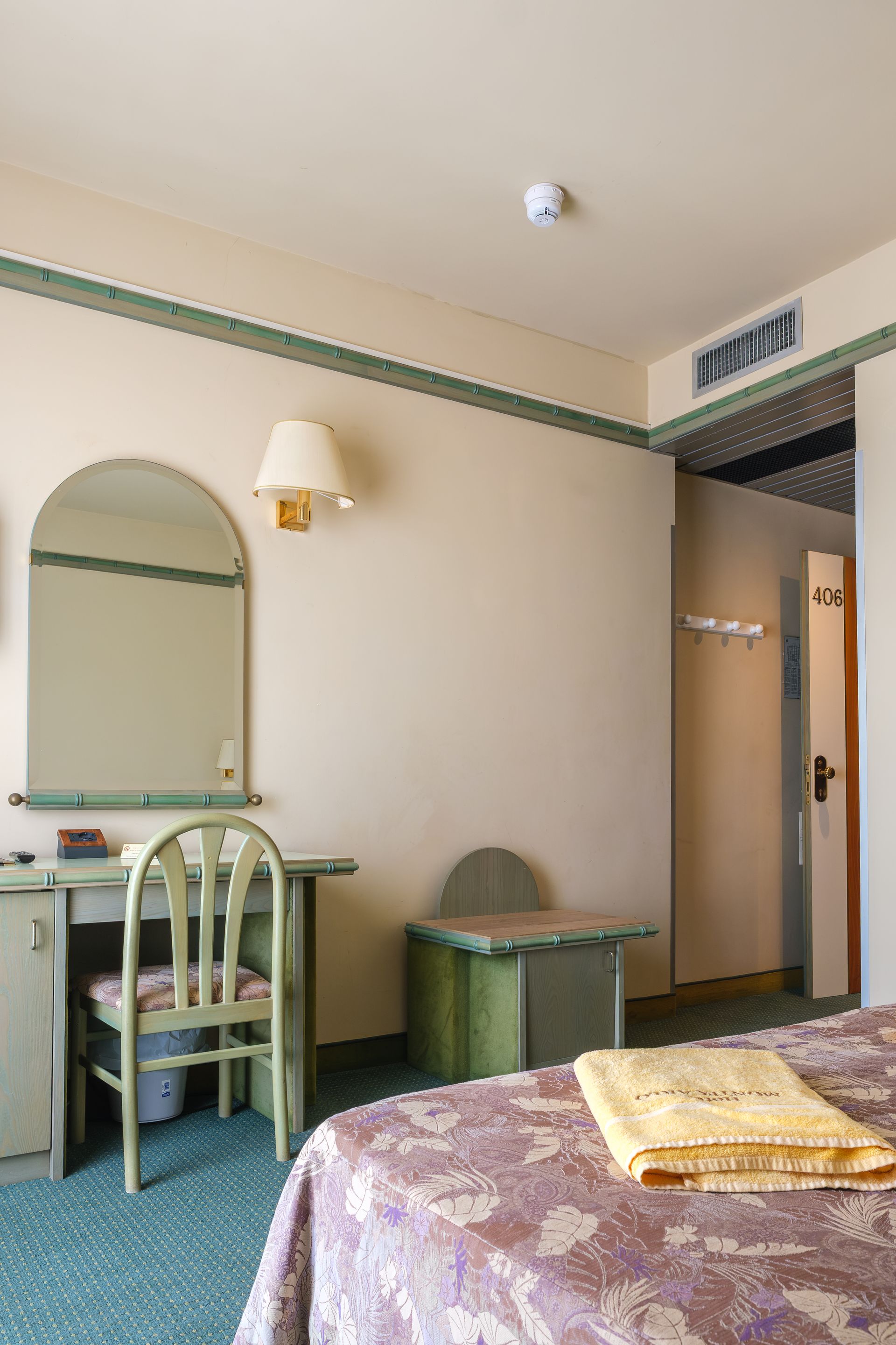 Una stanza d'albergo con un letto, una scrivania, una sedia e uno specchio.