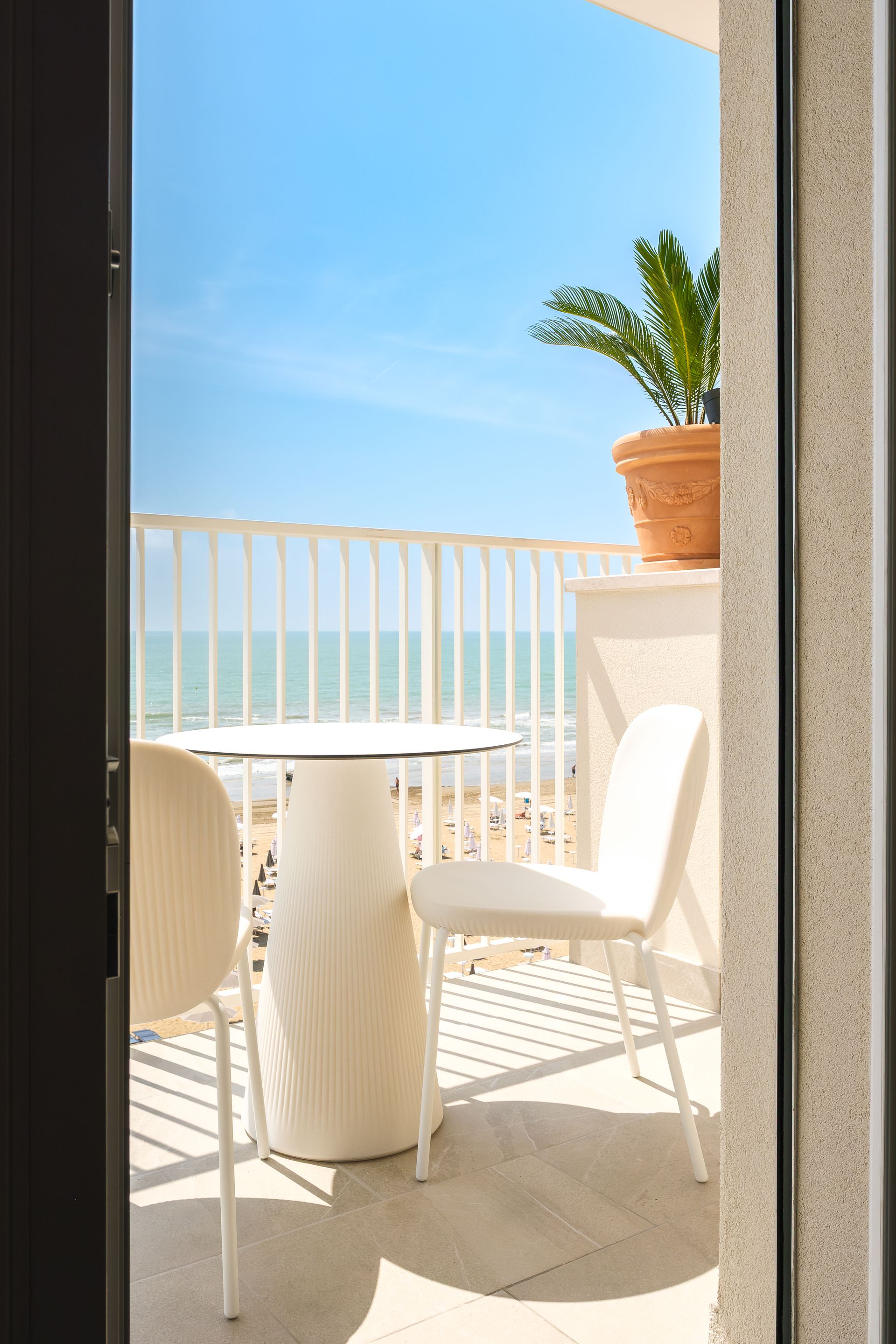 Un balcone con tavolo e sedie con vista sull'oceano.