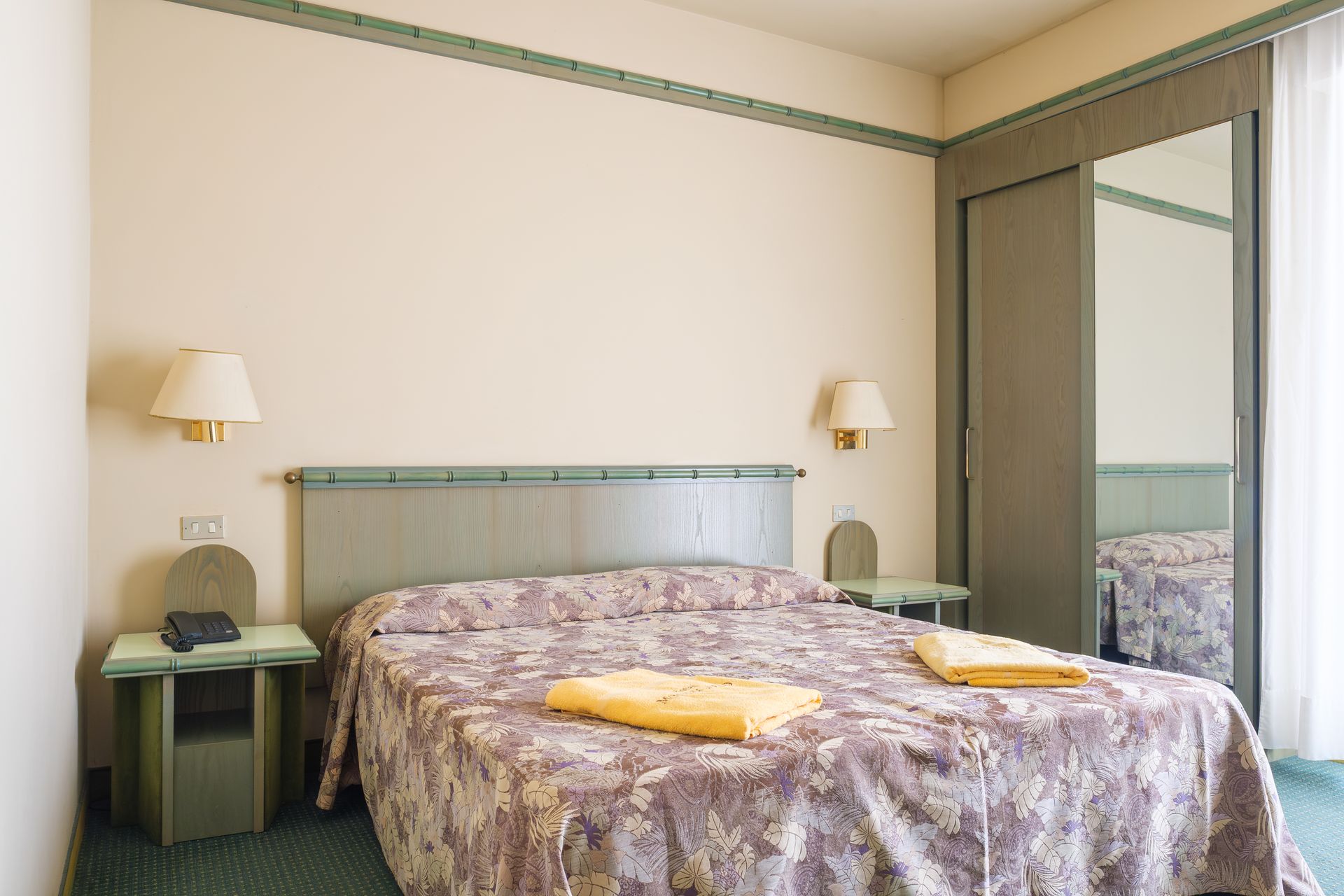 Una camera d'albergo con un letto grande e uno specchio.