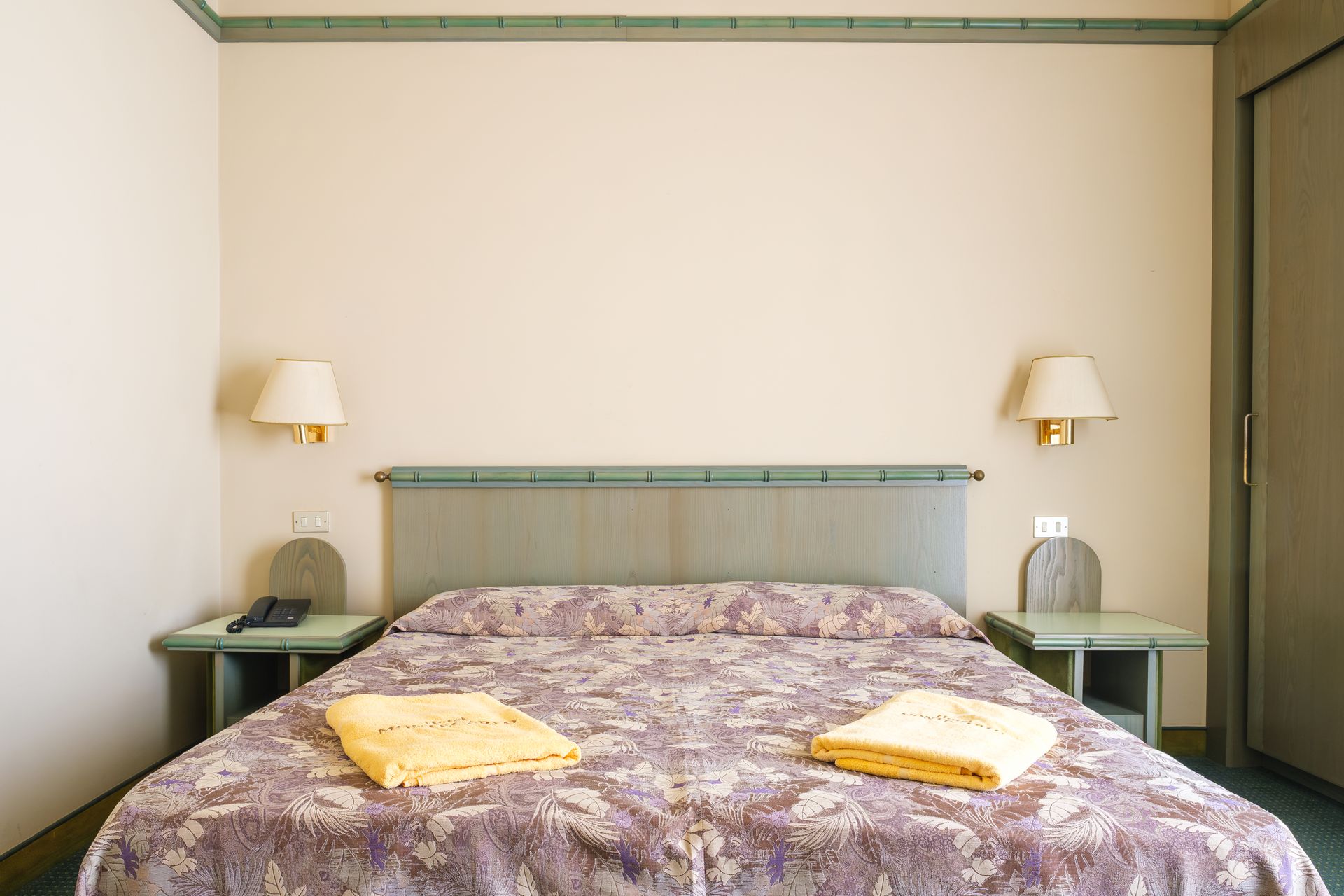 Una camera d'albergo con un letto e due comodini.