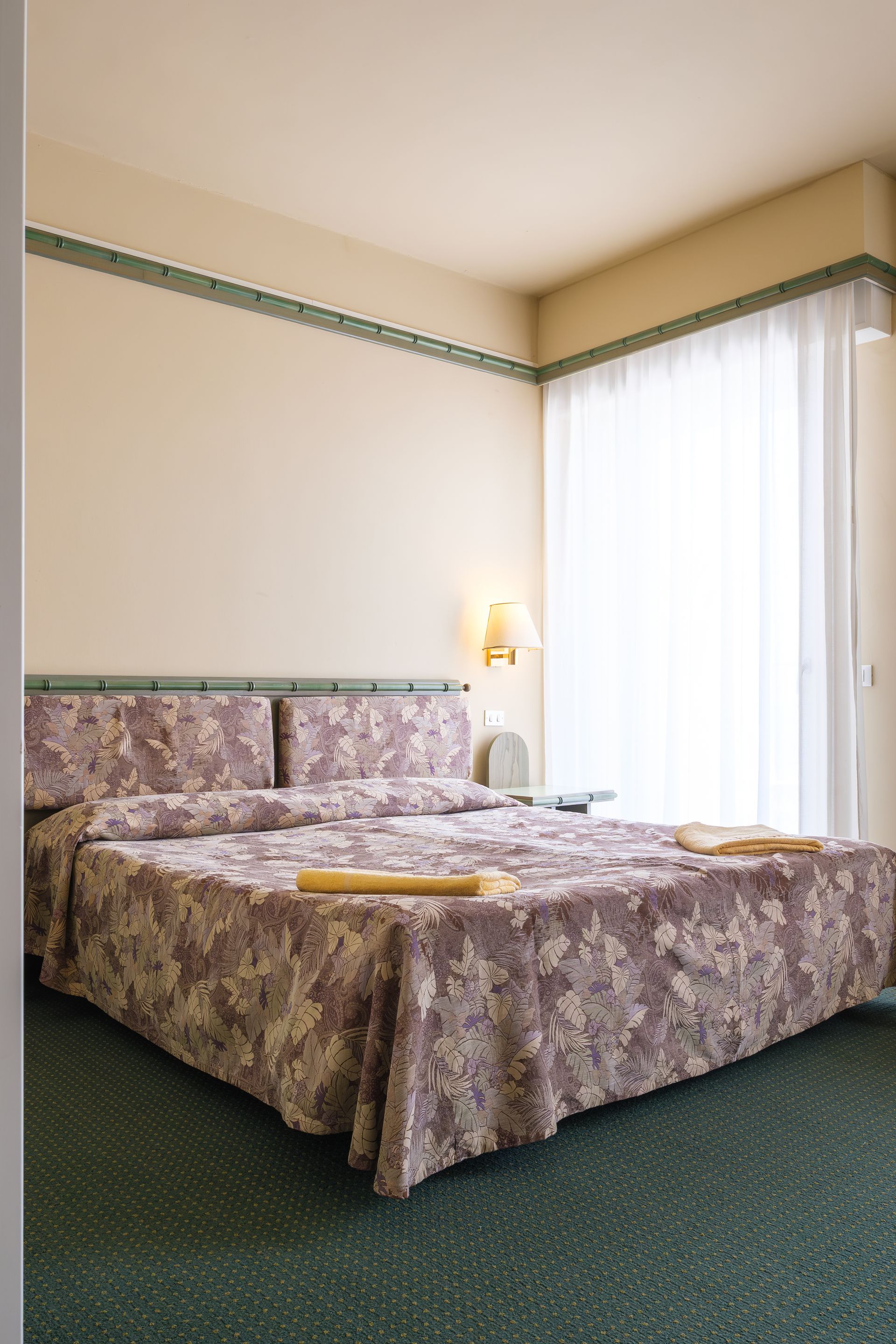 Una camera d'albergo con un letto e una porta scorrevole in vetro.