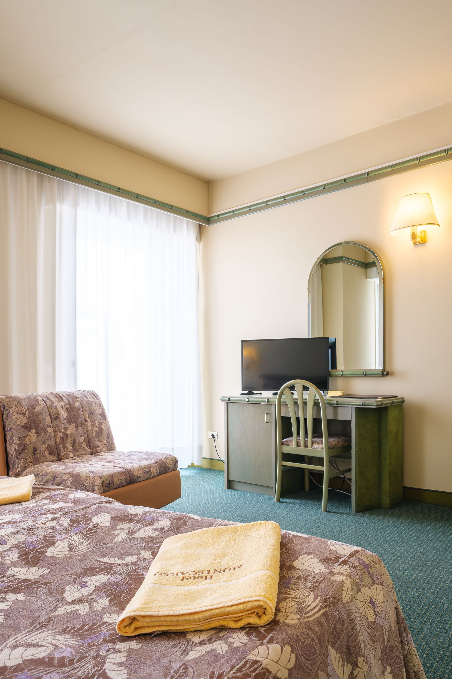 Una camera d'albergo con un letto, una scrivania, una sedia e una televisione.