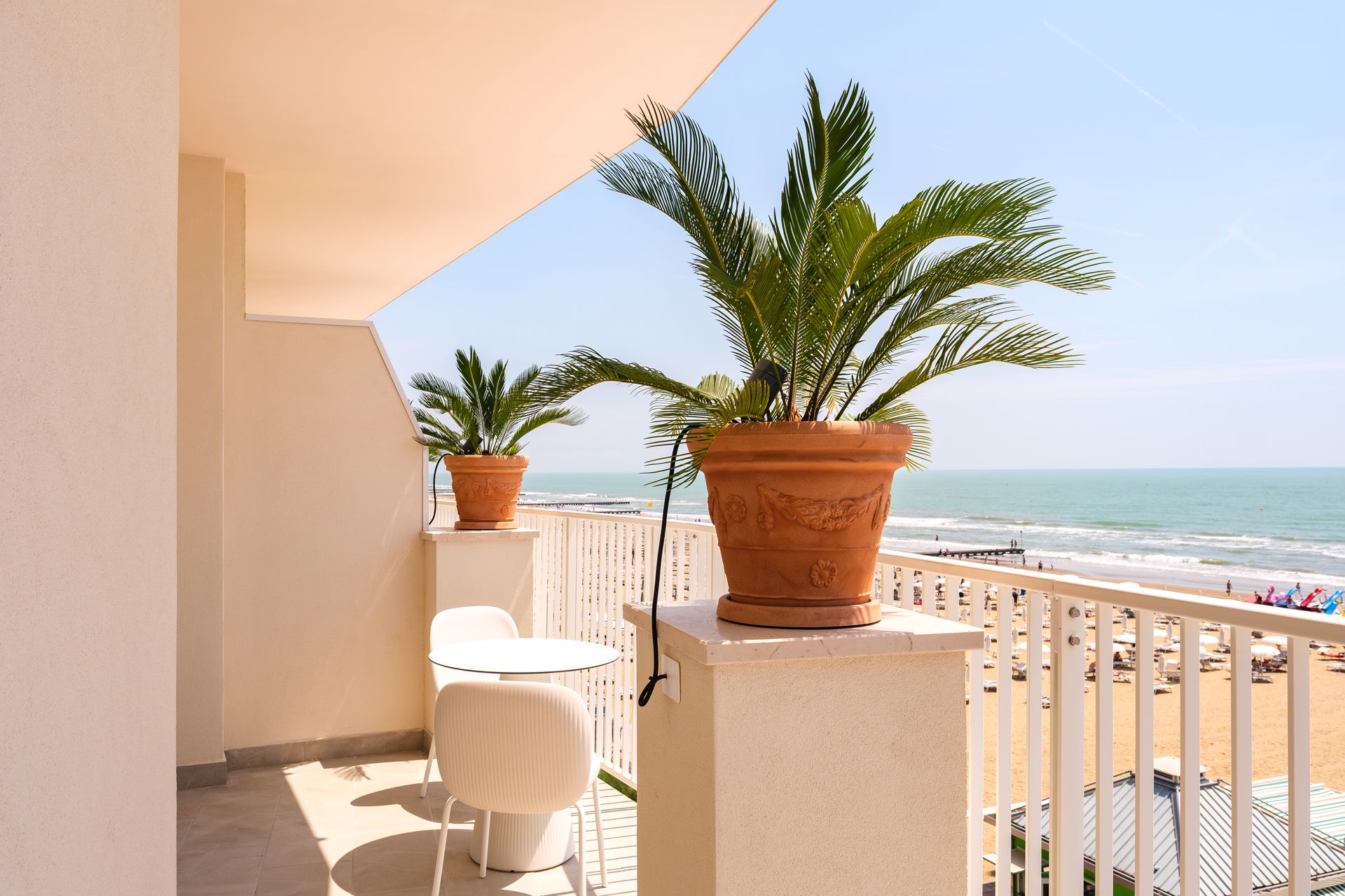 Un balcone con tavolo, sedie e piante in vaso con vista sull'oceano.