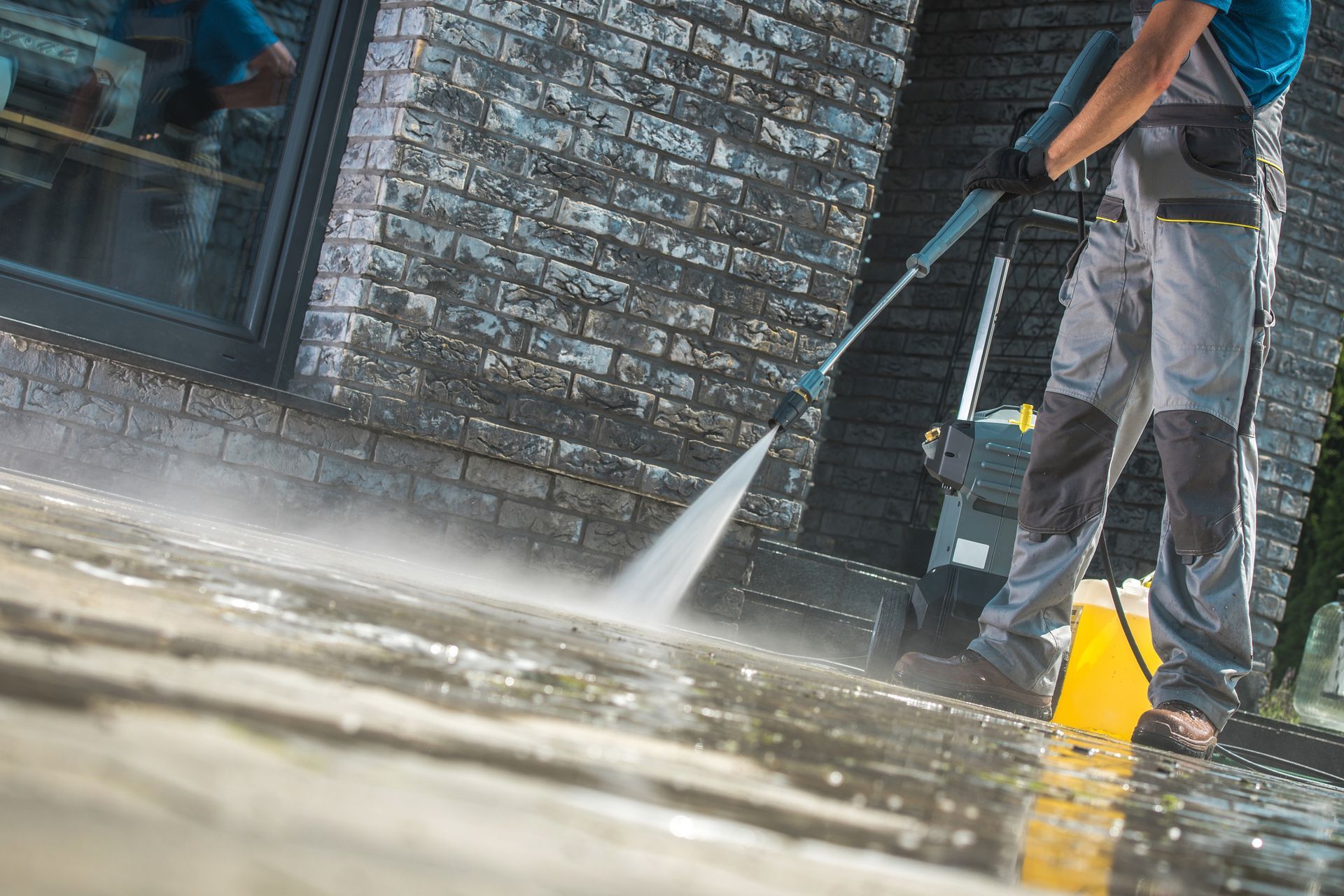 A man is using a high pressure washer to clean a driveway. A man is using a high pressure washer to clean a driveway.