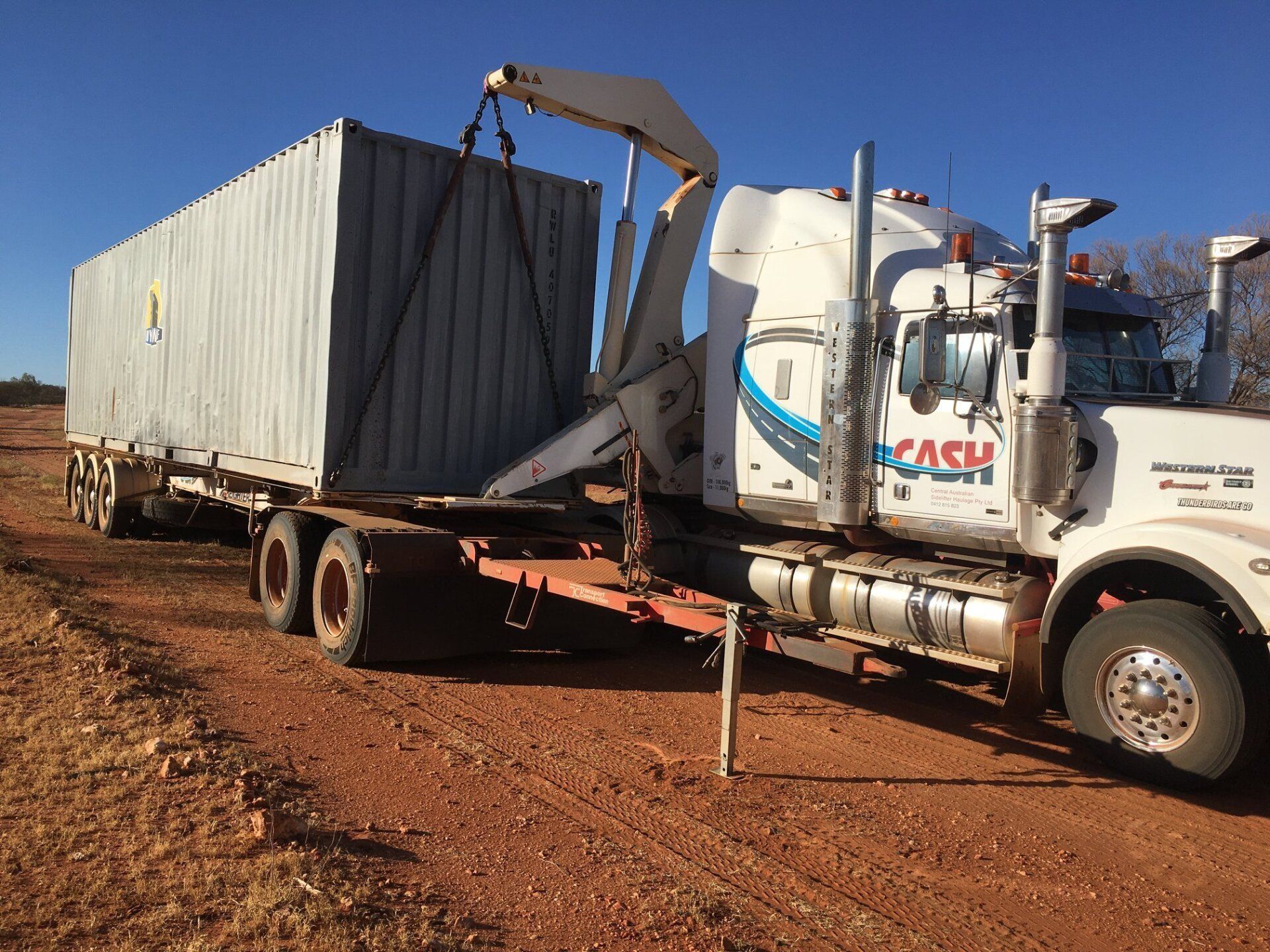 Truck with Crane Lifting a Shipping Container on A Red Dirt Road — Central Australian Sidelifter Haulage in Ciccone, NT