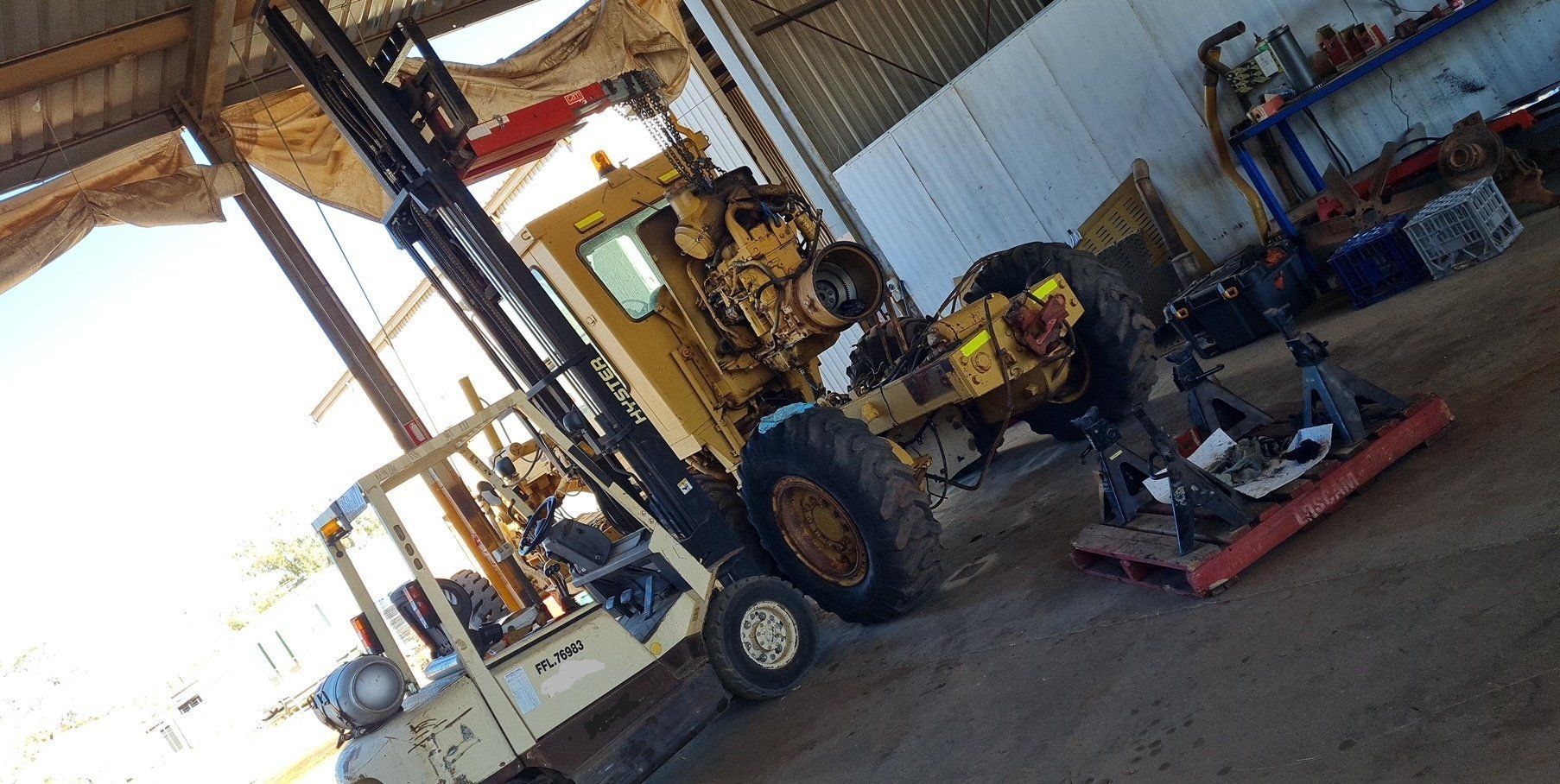 A Forklift Inside a Shed Next to Machinery Parts — Central Australian Sidelifter Haulage in Ciccone, NT