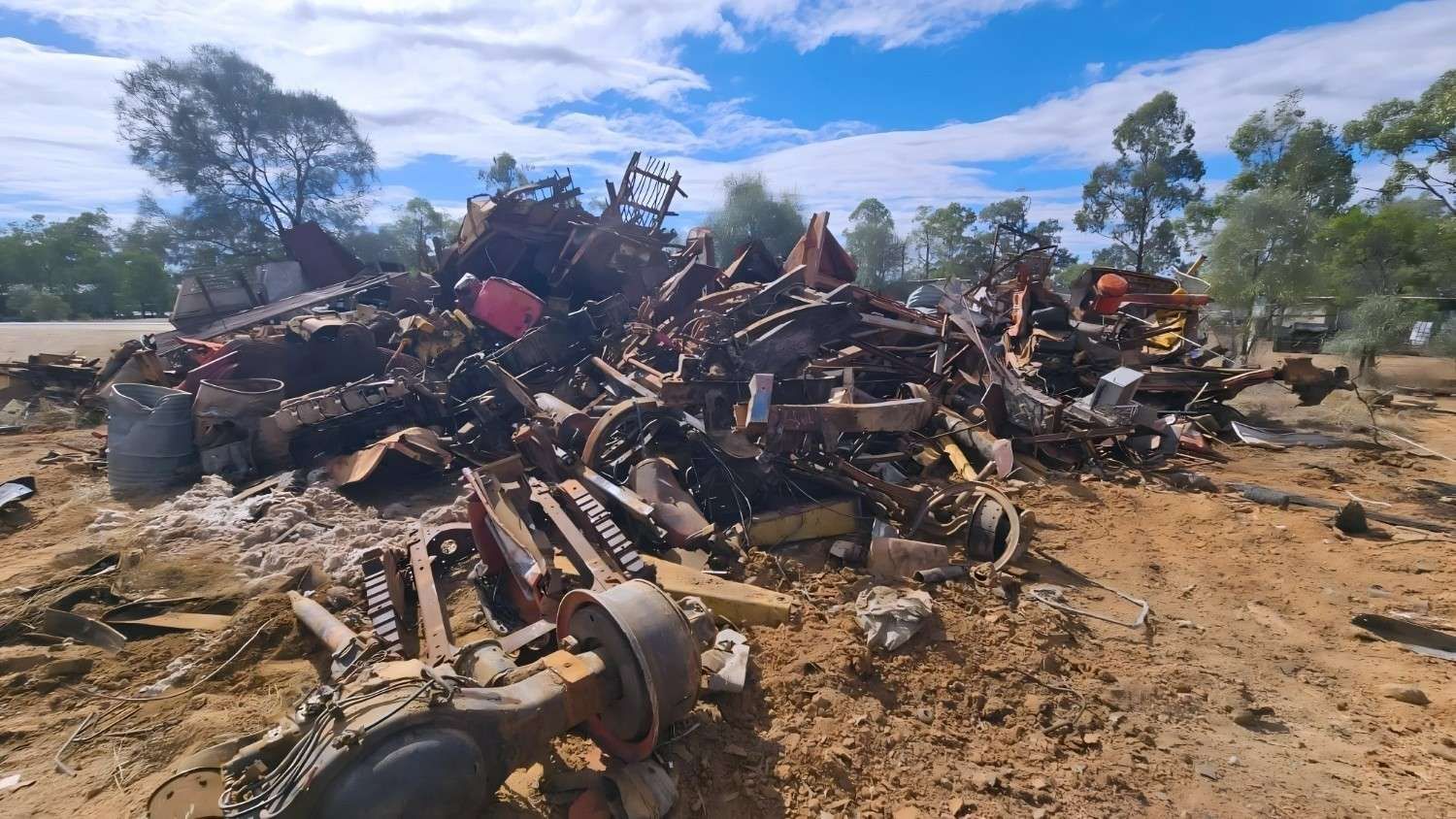 Pile of Scrap Metal in a Dirt Field, With Trees and a Blue Sky in the Background — NPX Solutions In Yeppoon, QLD