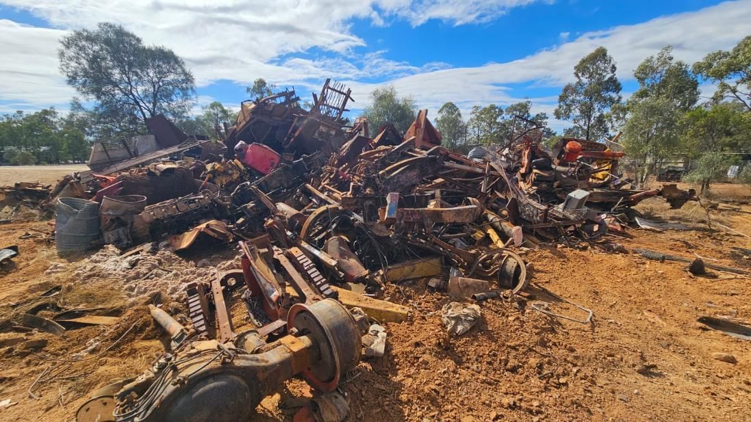 Pile of Rusty Metal Scraps and Vehicle Parts on Dry, Reddish Earth Trees — NPX Solutions In Gympie, QLD