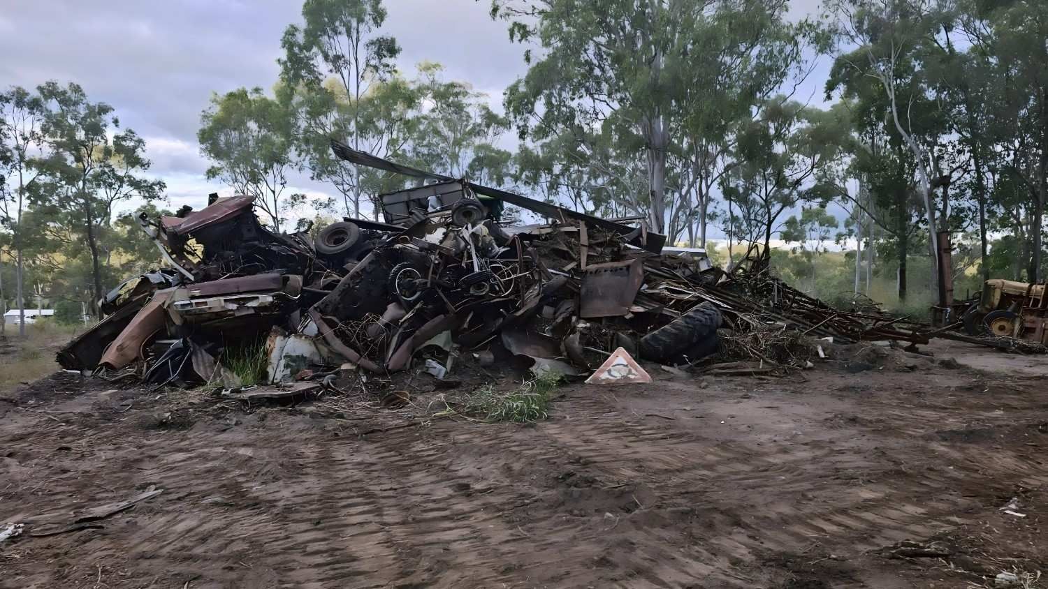 Pile of Metal Scrap in an Outdoor Setting, Including Wheels and Car Parts, With Trees — NPX Solutions In Biloela, QLD