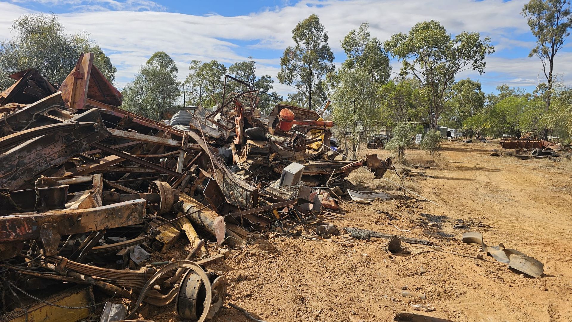Pile of Rusty Metal, Possibly Scrap, Next to a Dirt Road in a Dry, Wooded Area — NPX Solutions In Gympie, QLD
