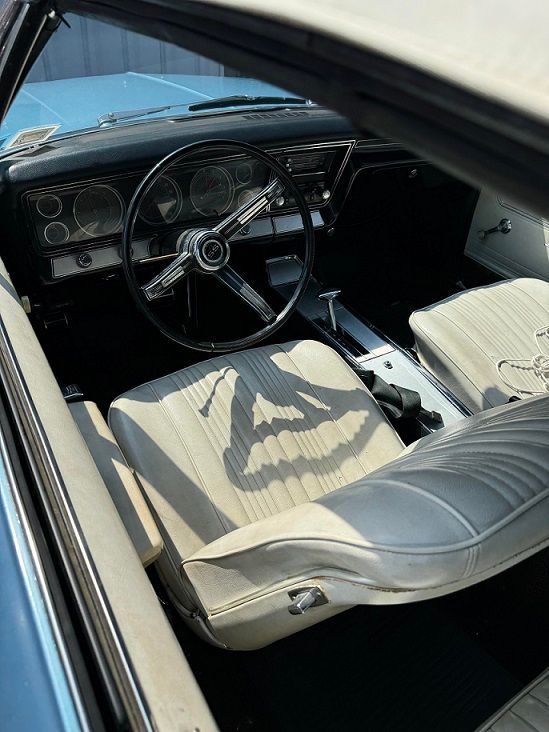 Interior view of a vintage light blue convertible with white seats and a black dashboard.