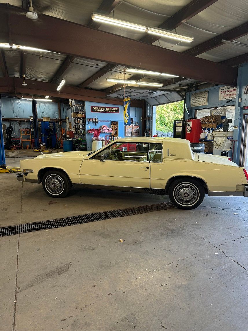 Yellow classic car parked inside a garage with open bay door.
