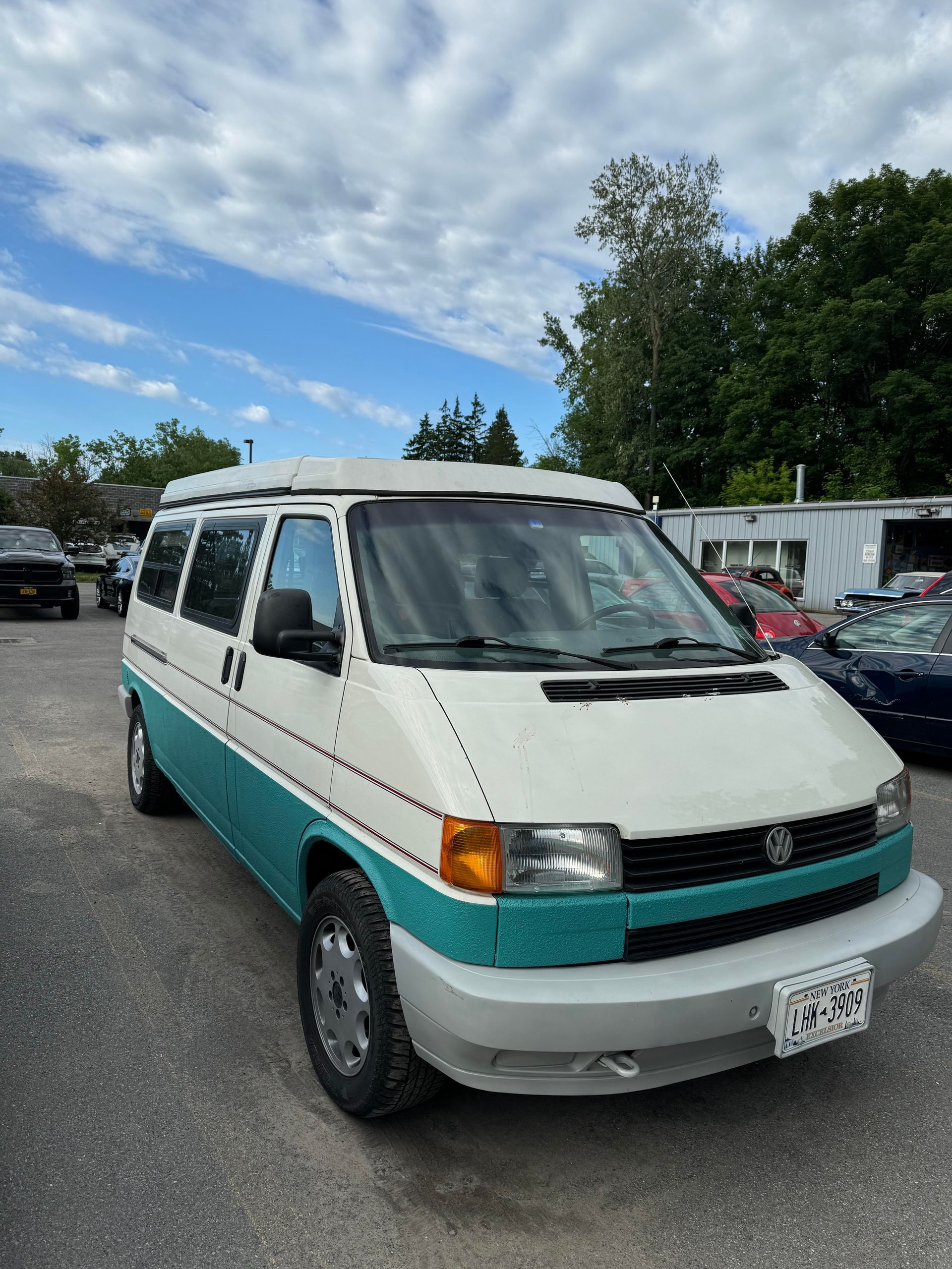 White and teal Volkswagen campervan parked on asphalt.