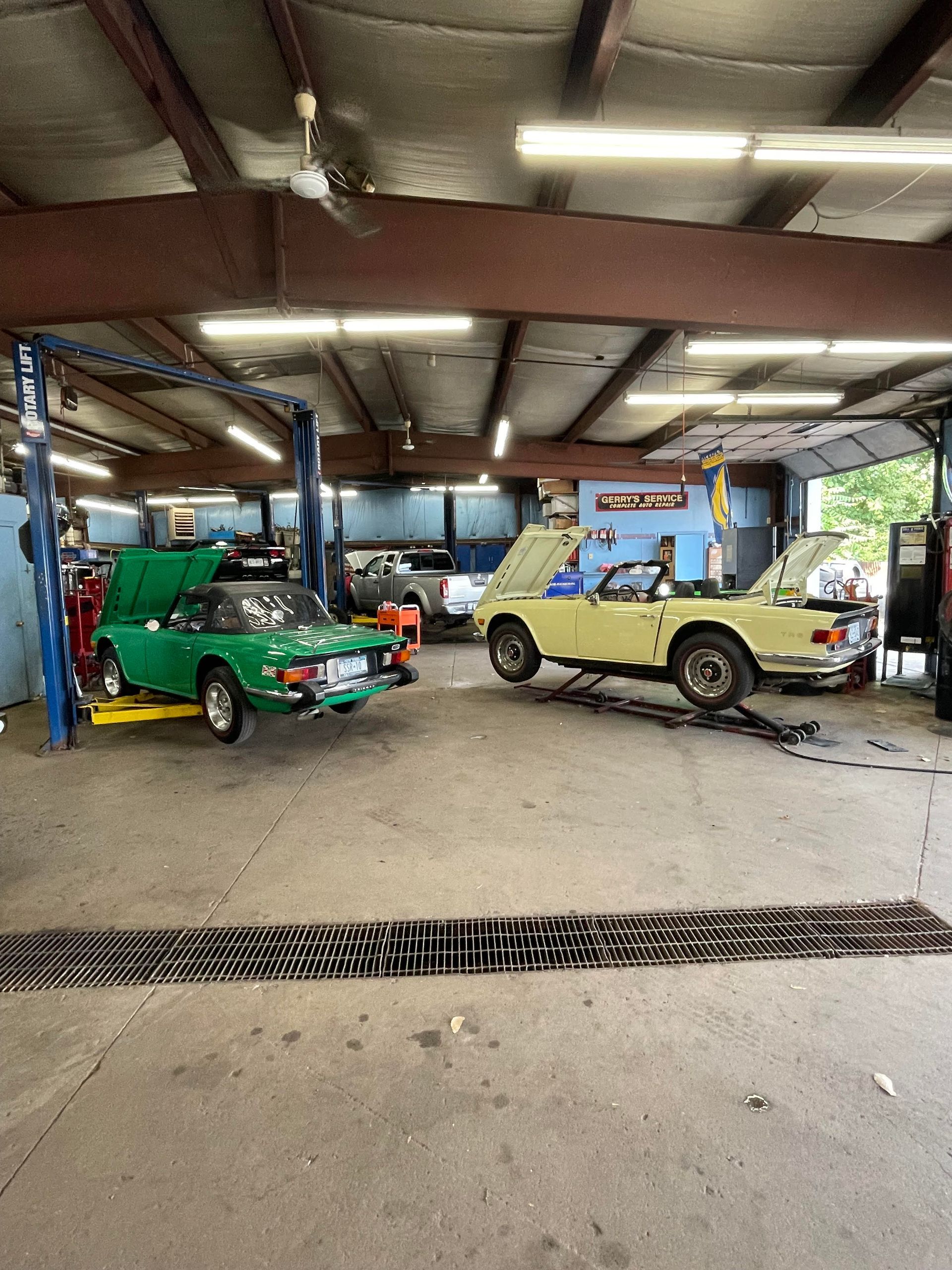 Cars being serviced in a garage; a green and a yellow sports car are on lifts.