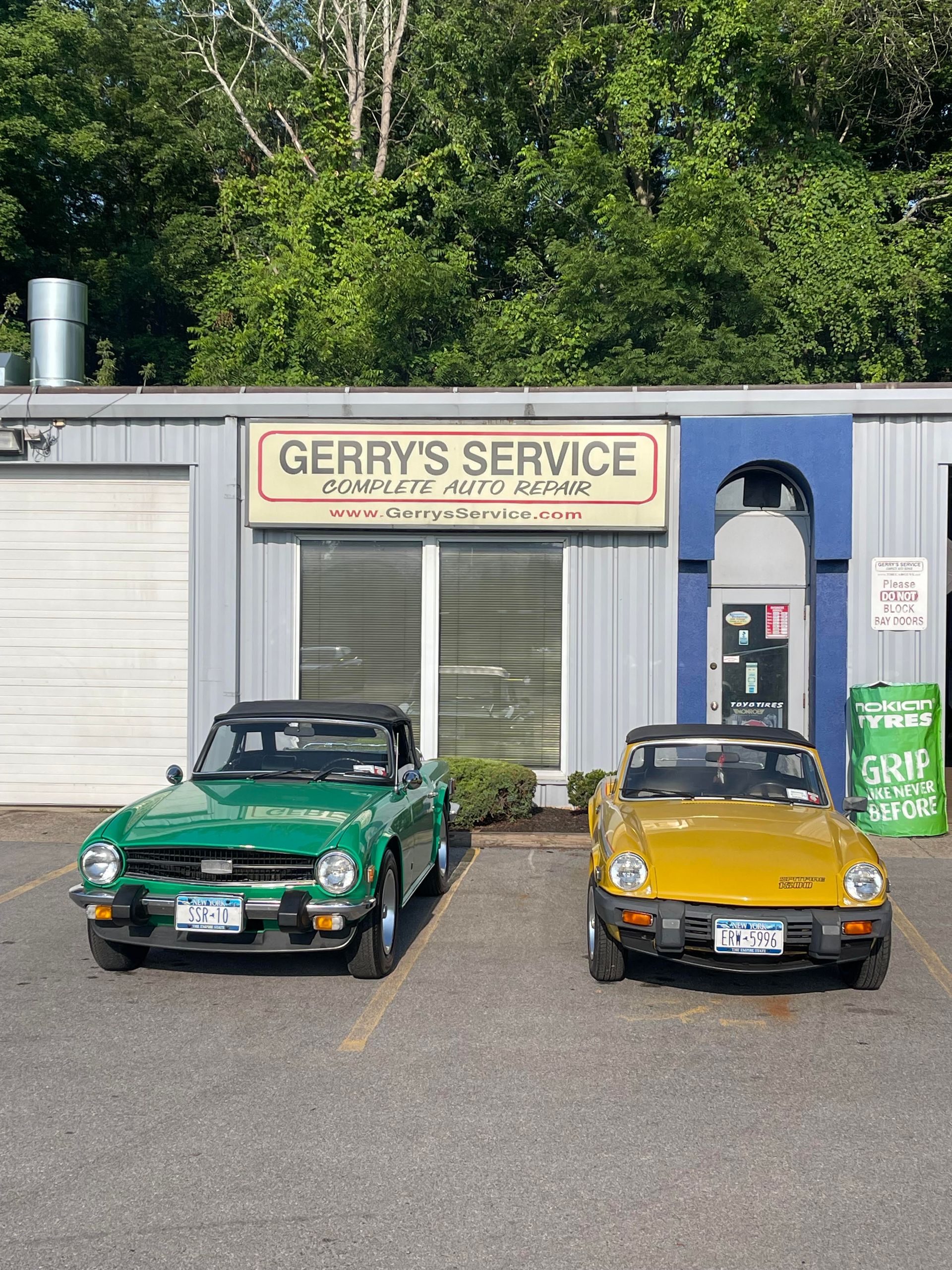Two classic convertible cars, green and yellow, parked in front of 