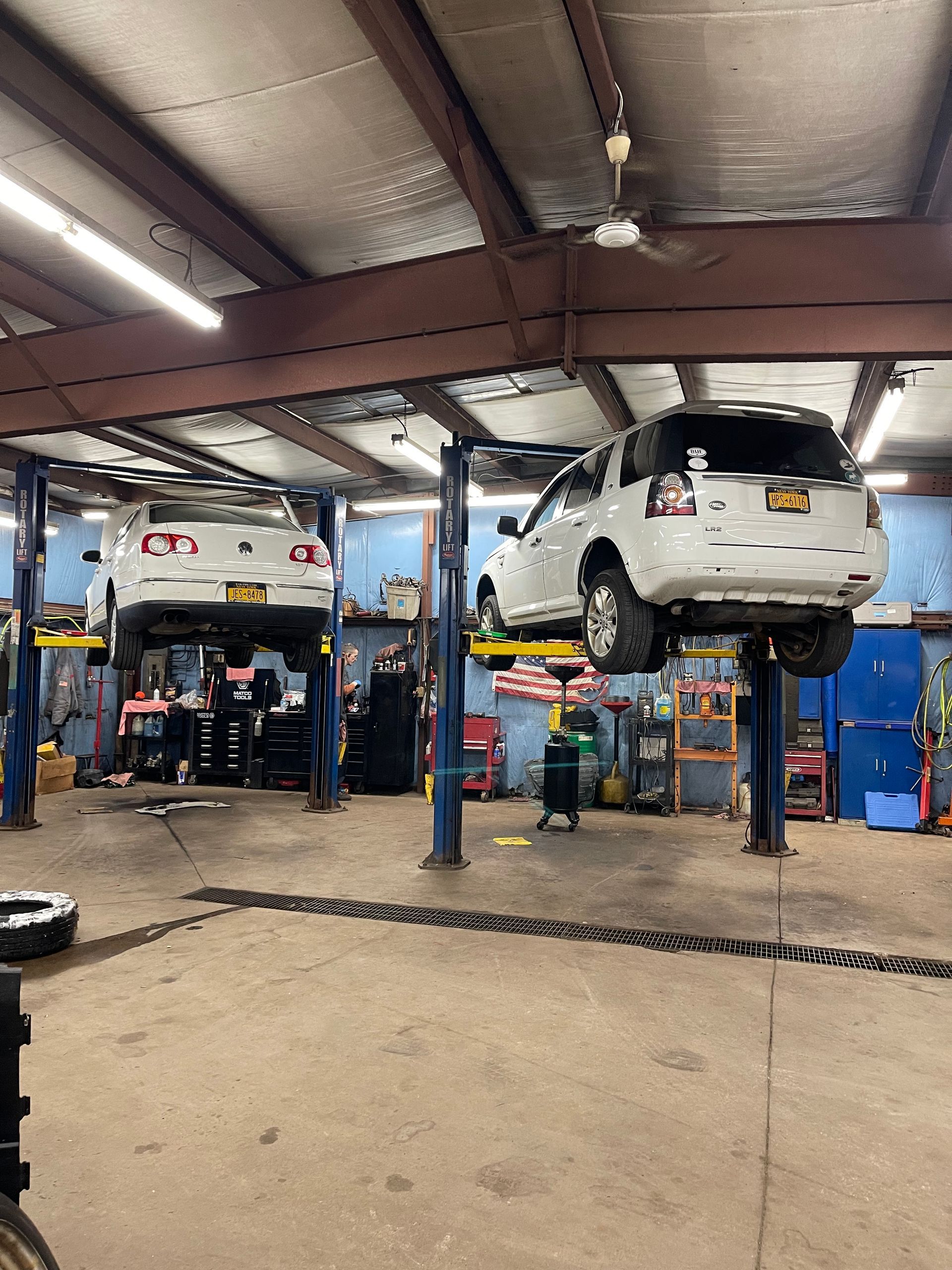 Cars raised on lifts in a mechanic's garage, with tools and equipment visible.