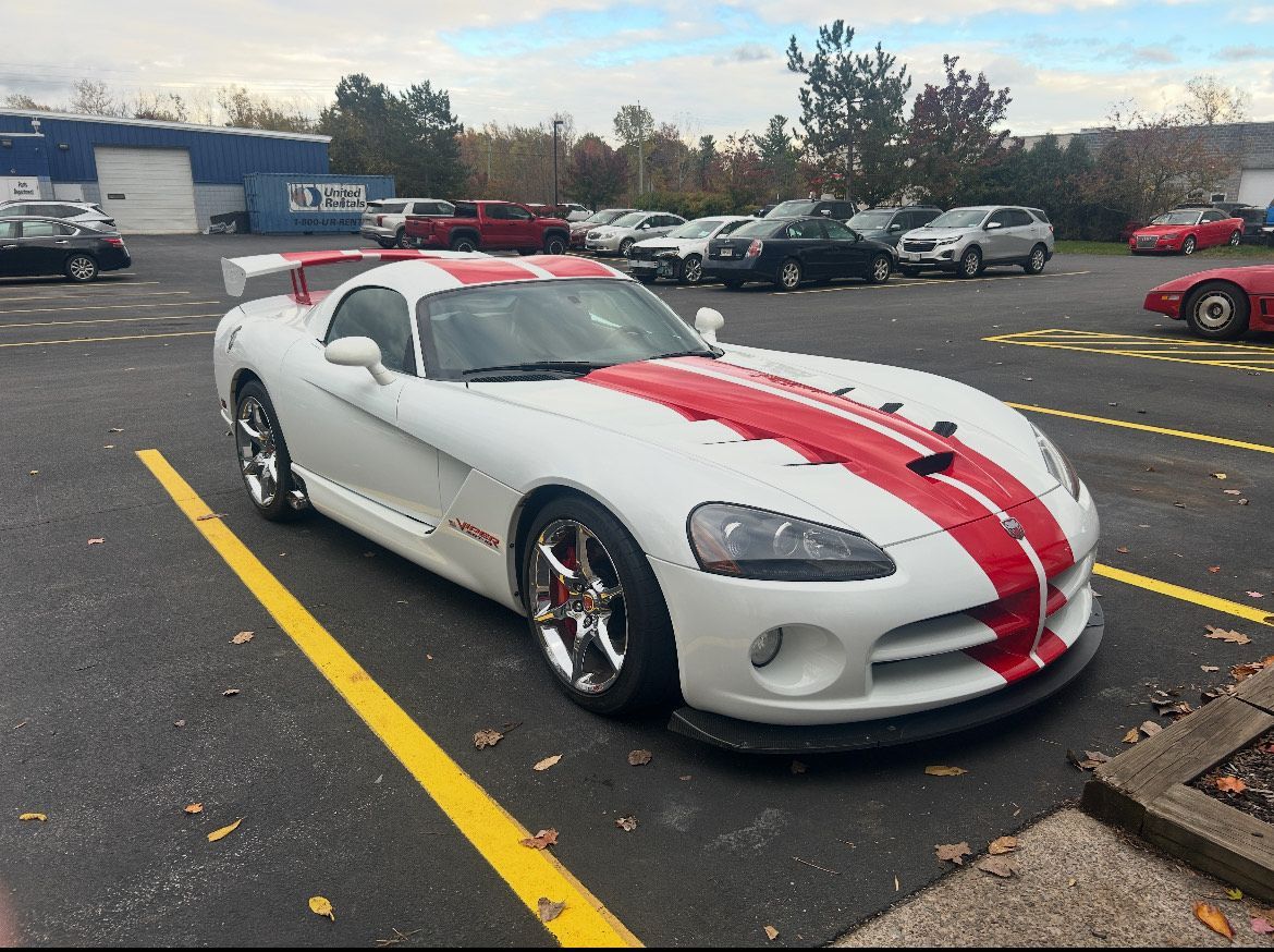 White Dodge Viper with red stripes parked in a lot, sunny day.