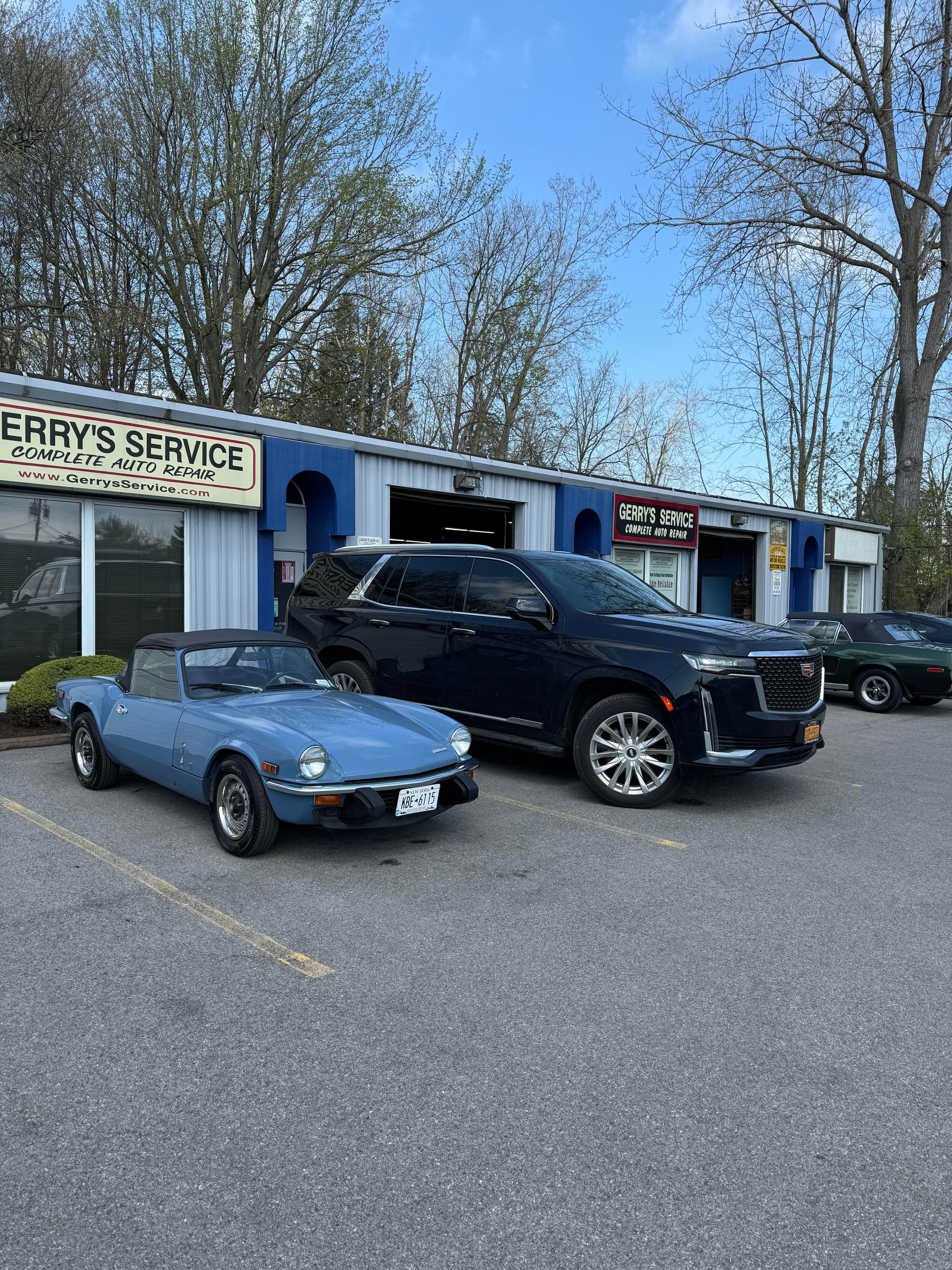 Blue convertible and black SUV parked in front of 